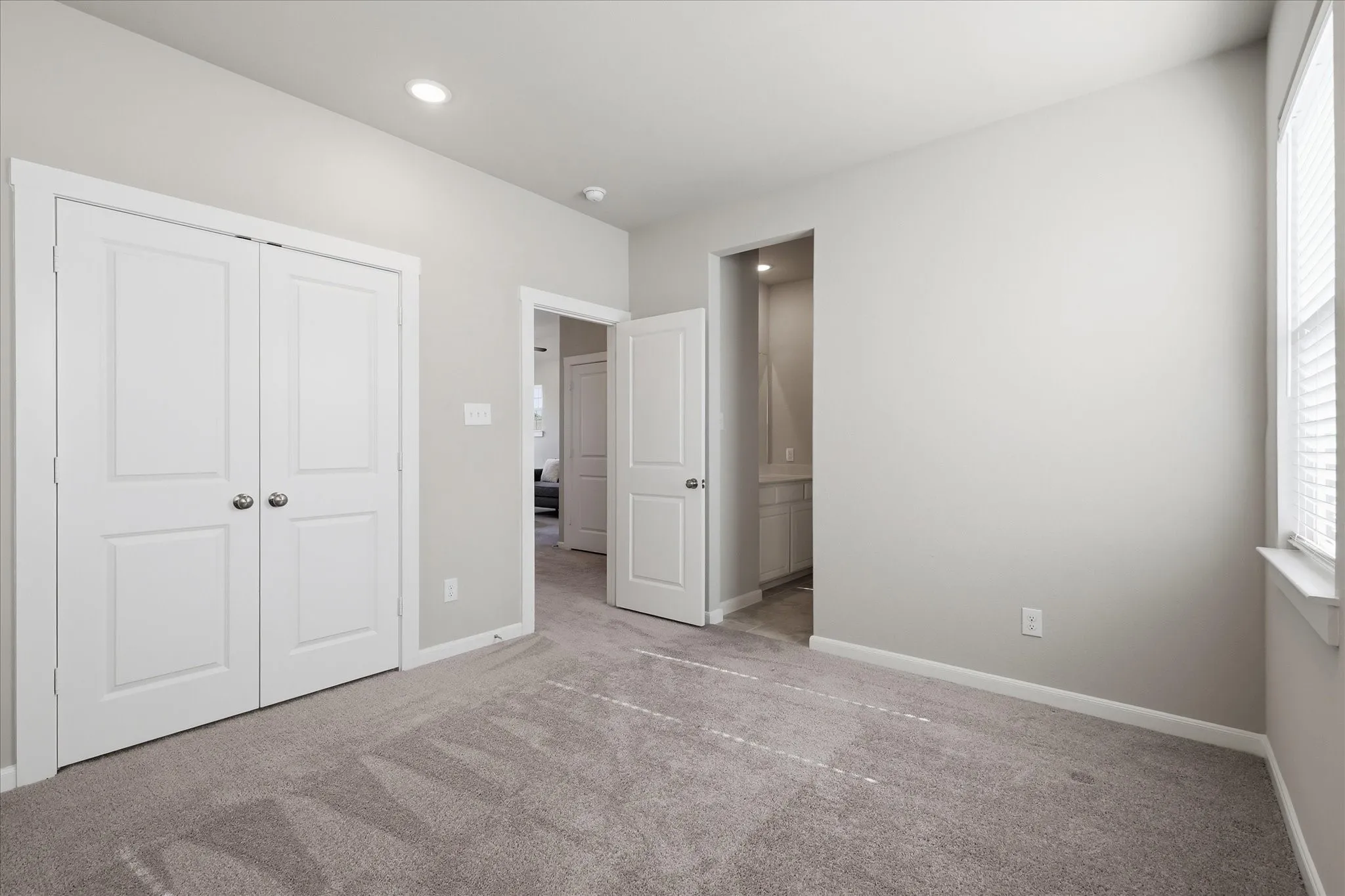 Recessed ceiling lighting, white interior doors, and window with blinds
