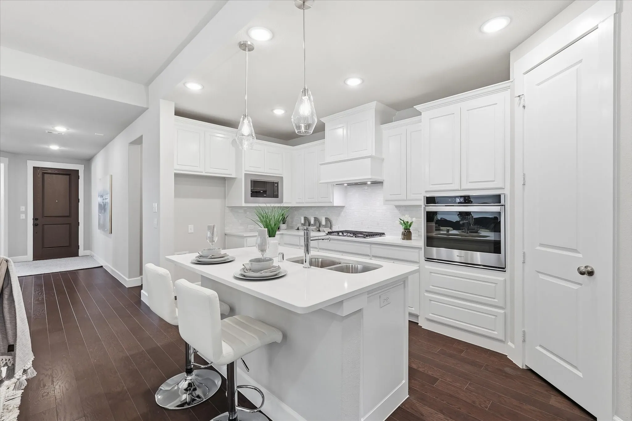 Kitchen featuring white cabinetry, built-in stainless steel oven, white countertops, a double basin sink, and wood-finish flooring