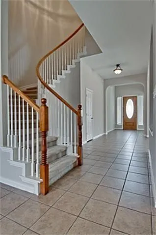 Sweeping staircase with wood handrails and white balusters