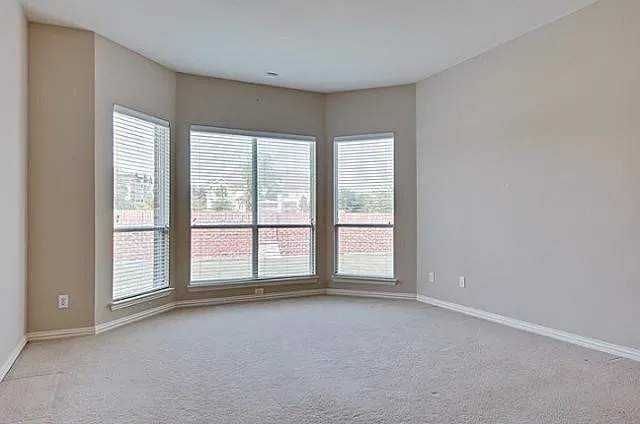 Bright room featuring a large bay window, neutral wall paint, white trim, and light-colored carpeting