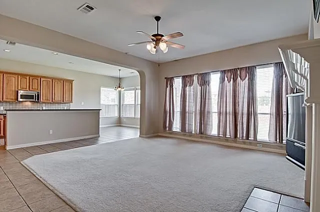 Spacious living area featuring carpet flooring, an arched doorway, and ample natural light from multiple windows