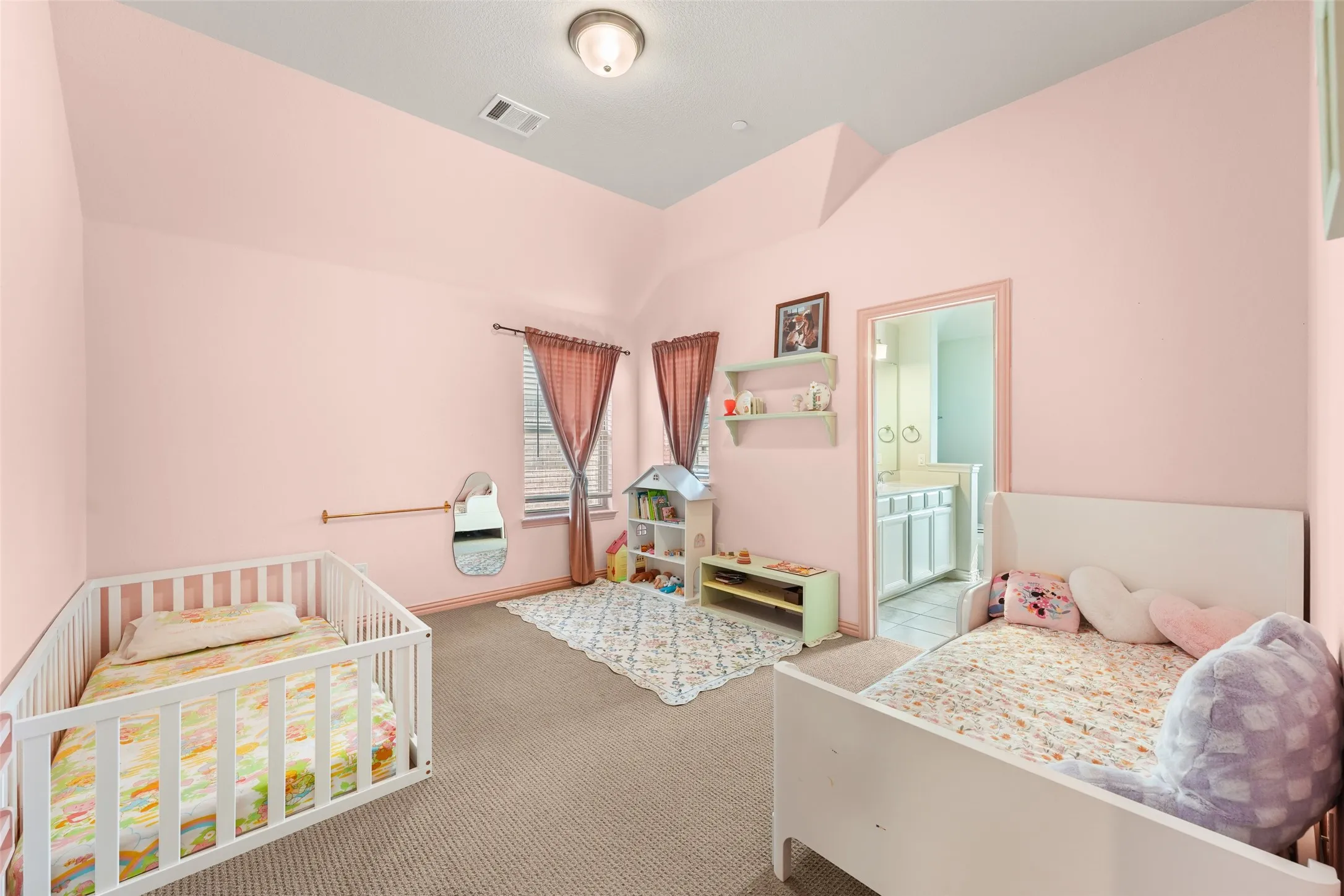 Carpeted room featuring vaulted ceilings and a doorway leading to a bathroom