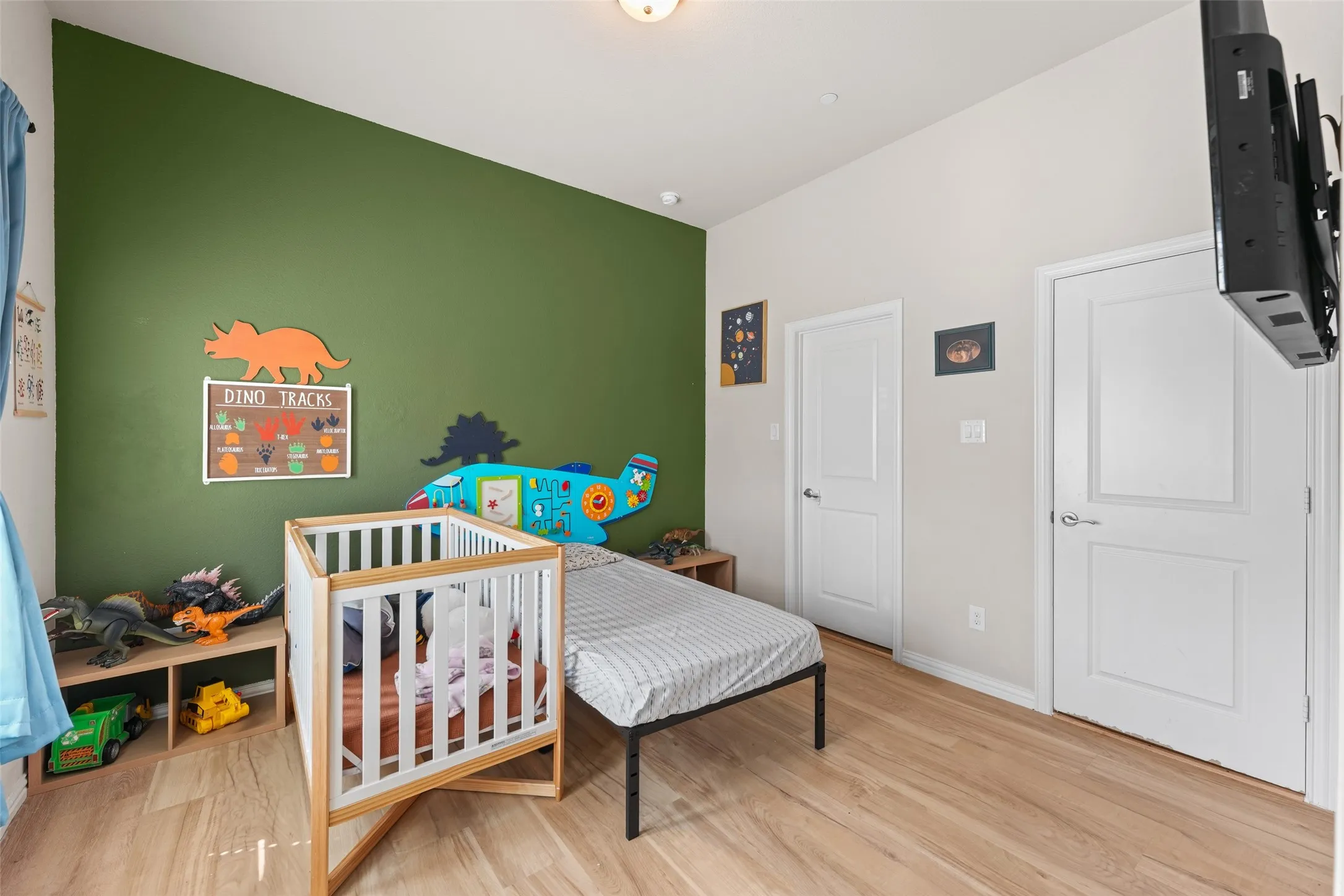 Room featuring light wood-finish flooring, a vibrant accent wall, and high vaulted ceilings