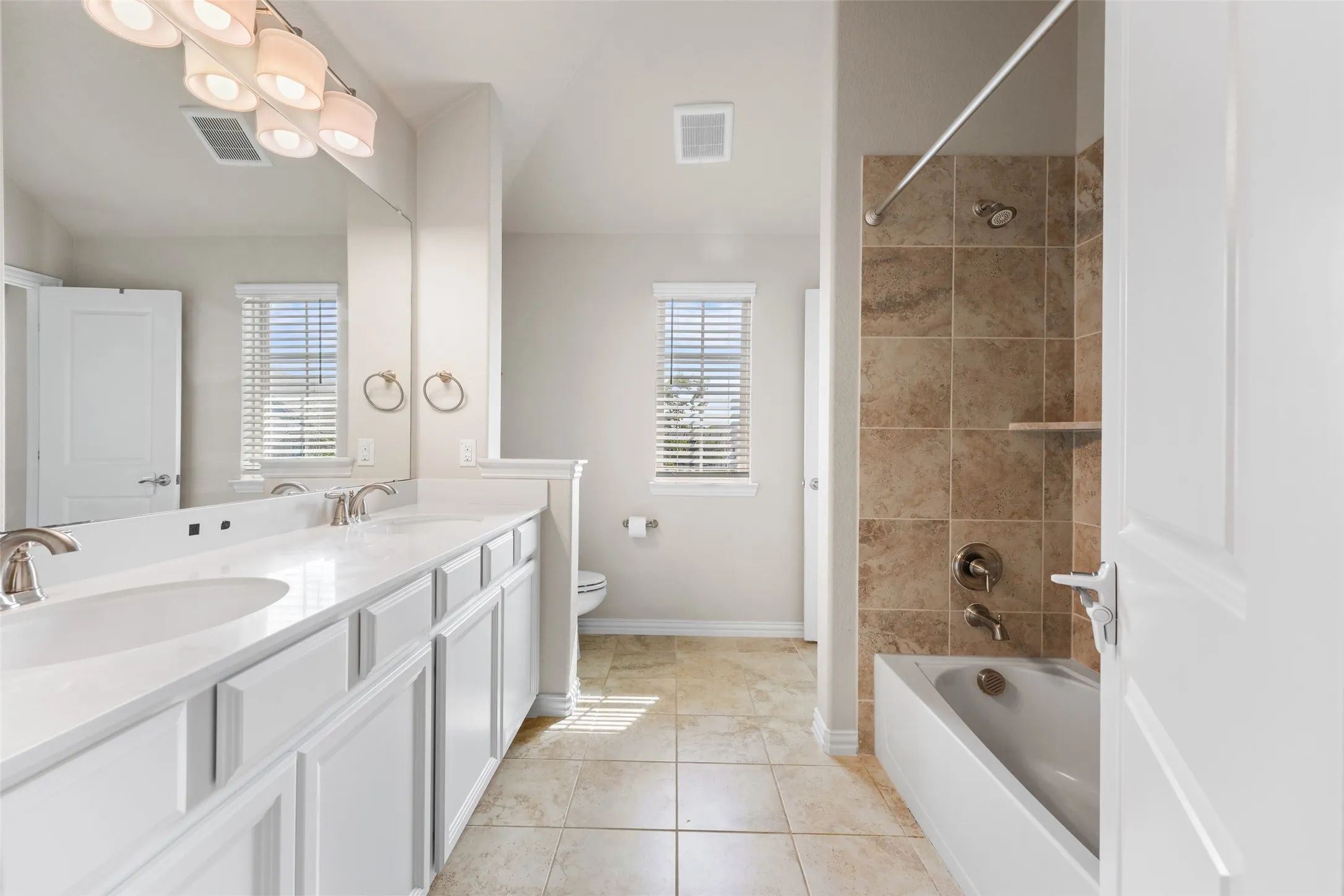 Bathroom featuring a dual vanity with white cabinetry, light-toned countertops, and brushed nickel fixtures
