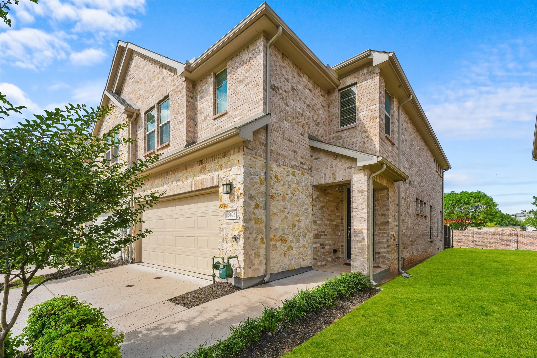 Two-story brick and stone facade residence featuring a covered entry, an attached garage, and multiple windows