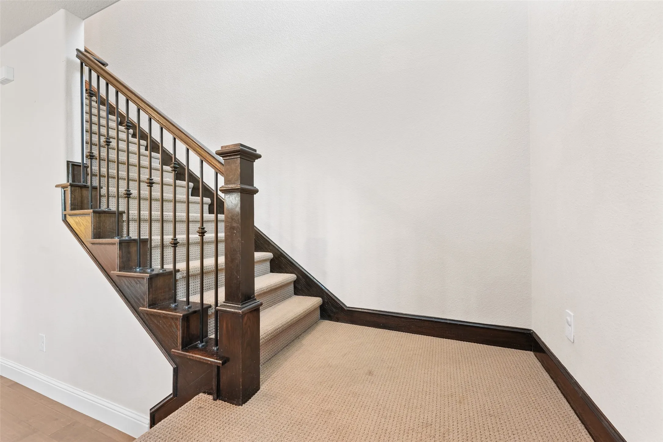 Elegant staircase featuring rich wood construction with metal spindle railing, geometric lattice detailing, and substantial newel posts