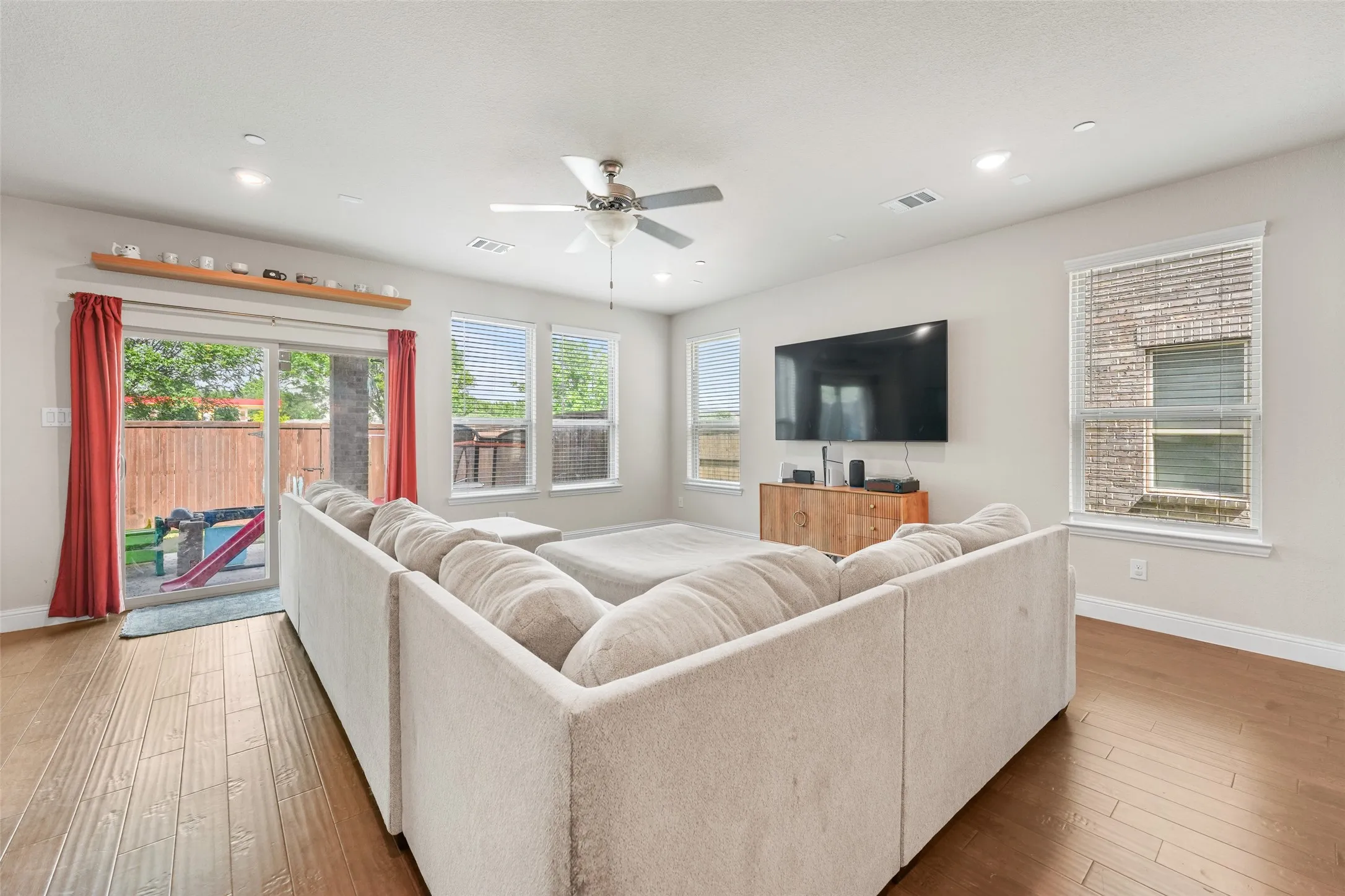 Spacious living area featuring wood-finish flooring, recessed lighting, and a ceiling fan
