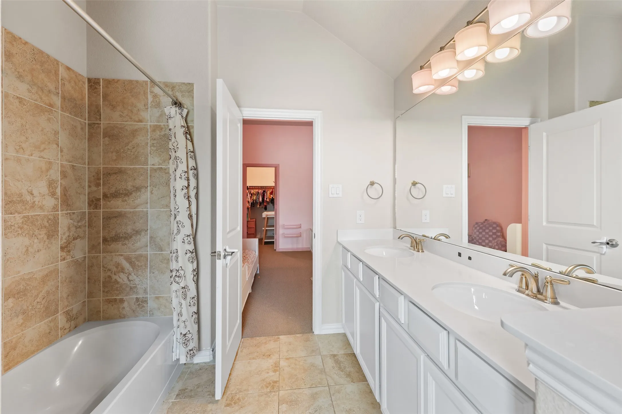 Bathroom featuring a double vanity with white cabinetry and integrated sinks, a full-width mirror, and a multi-bulb light fixture