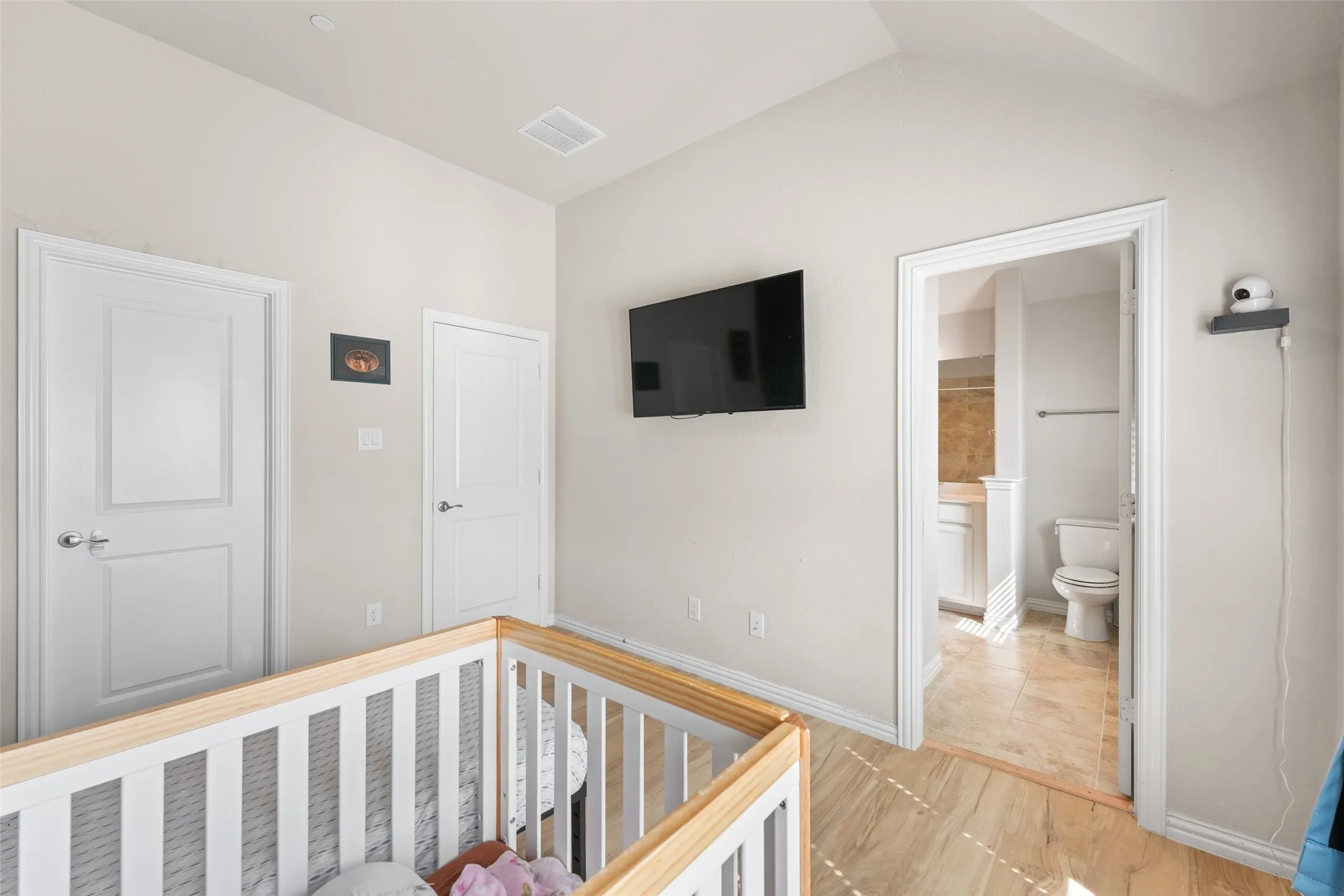 Light wood-finish flooring extending into a bright room with two panel doors