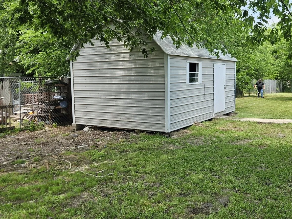 Detached storage shed with a window and solid panel door
