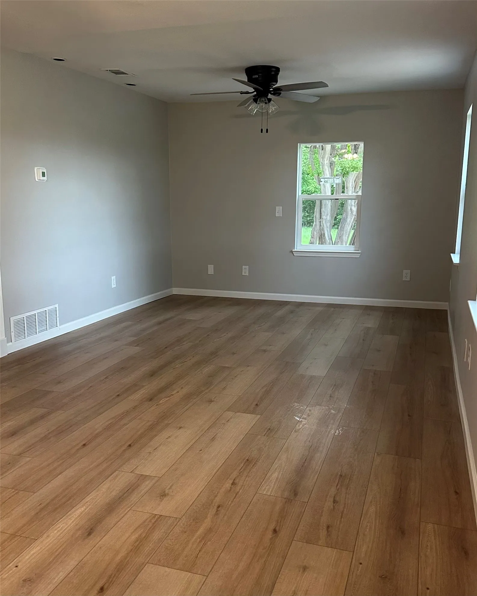 Wood-finish flooring with light gray walls, white trim, and a ceiling fan