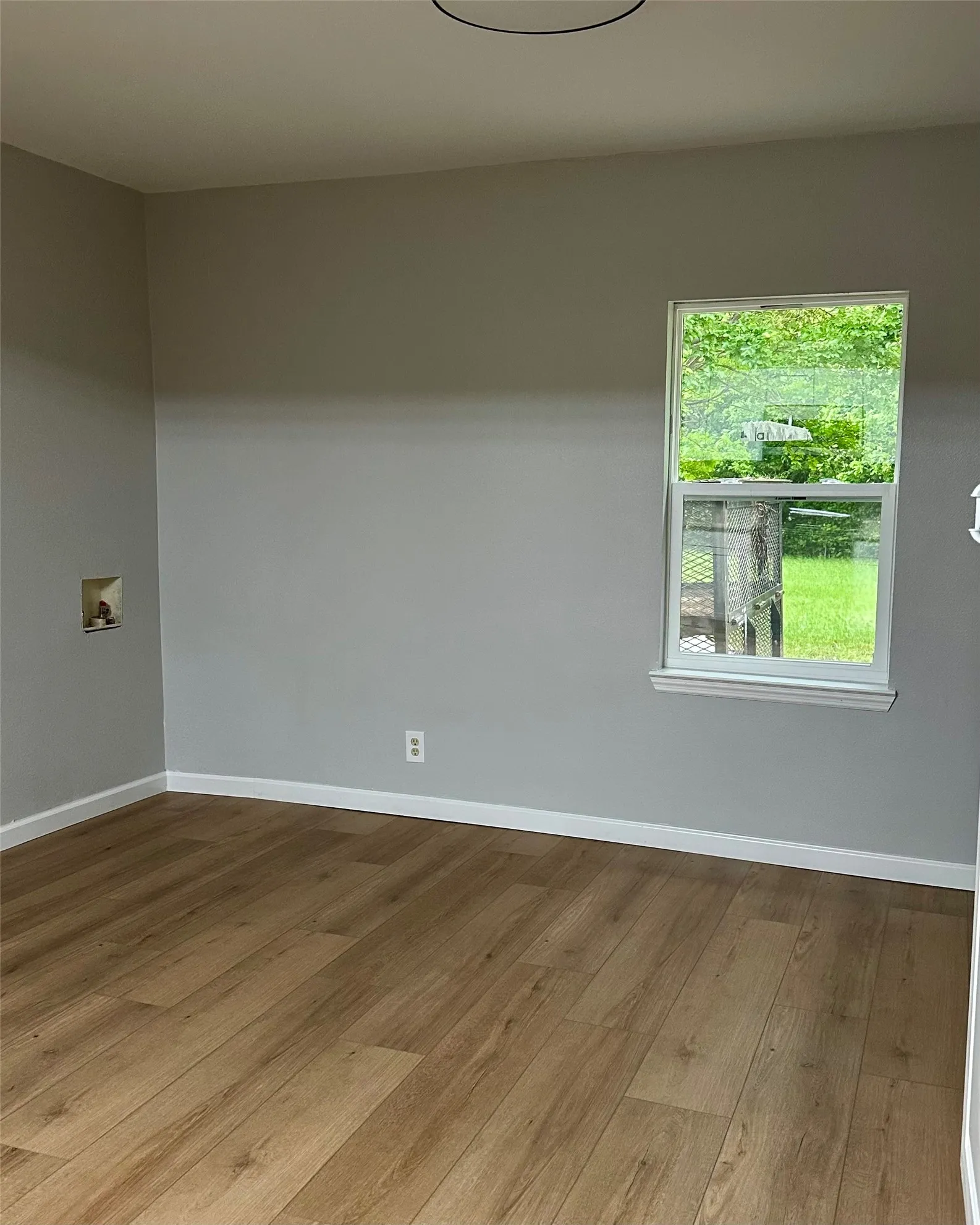 Wood-finish flooring, neutral wall tones, white trim, and a window with natural light