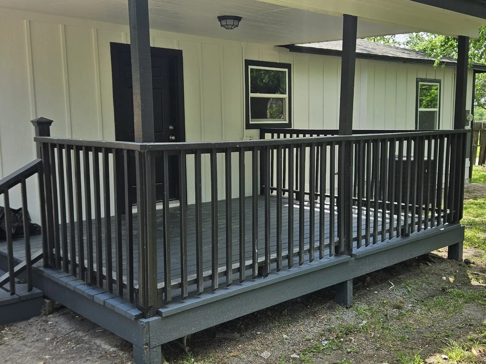 Covered porch featuring a dark railing, dark flooring, and a contrasting light exterior siding