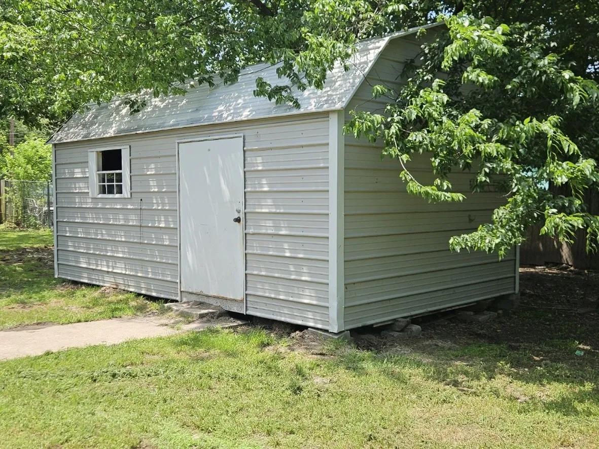 Detached storage shed with metal siding and a pitched metal roof