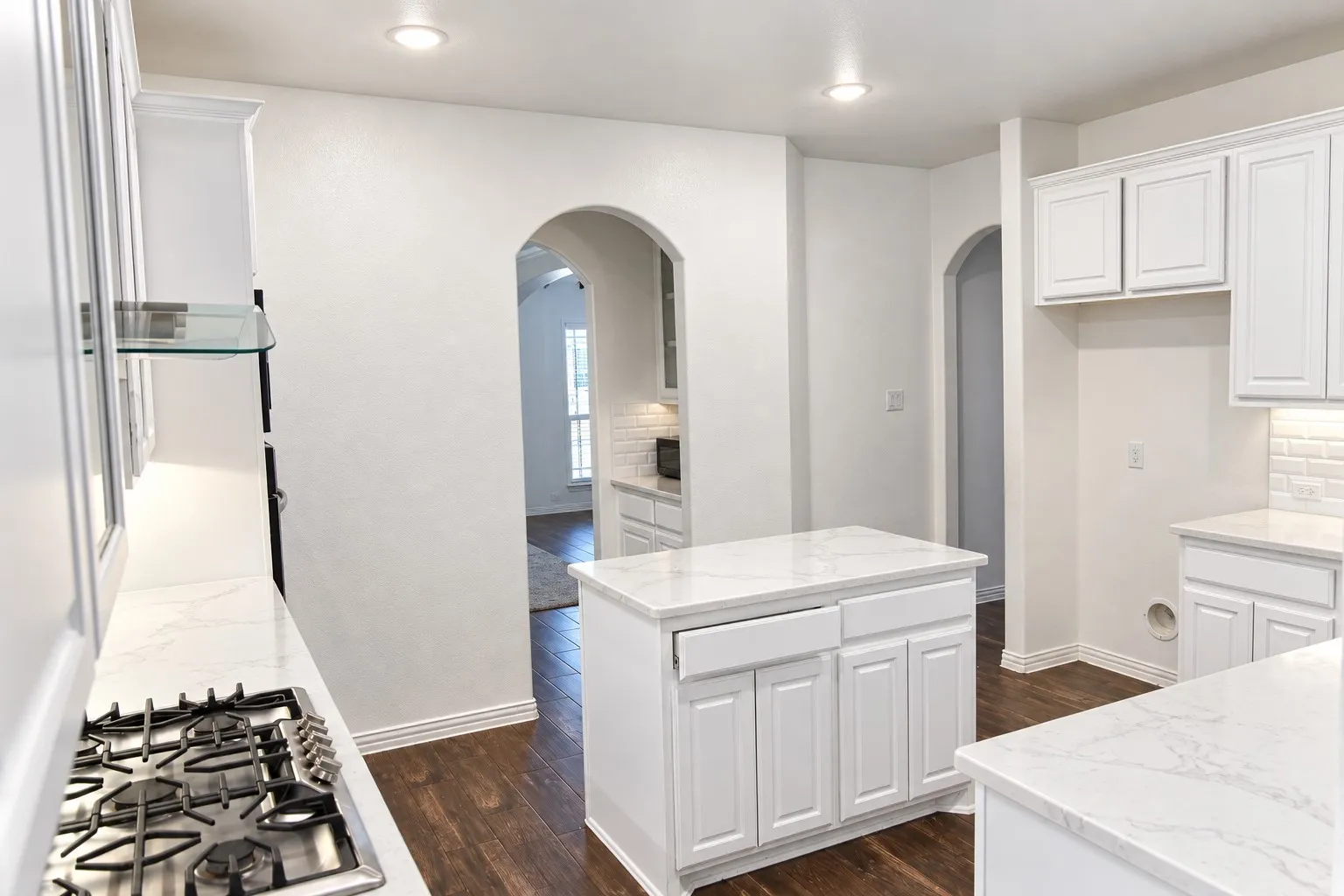 Kitchen featuring white cabinetry, stone-finish countertops, a central island, recessed lighting, and wood-finish flooring