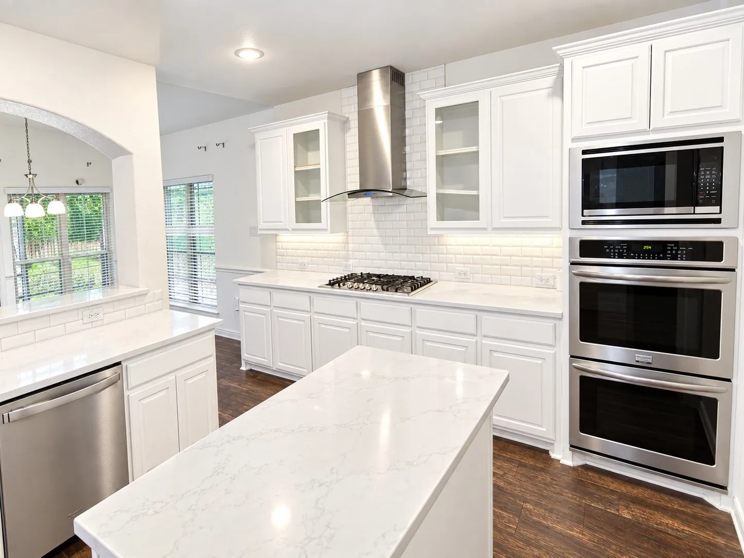 Kitchen featuring white cabinetry, stone countertops, stainless steel appliances, subway tile backsplash, and wood-finish flooring
