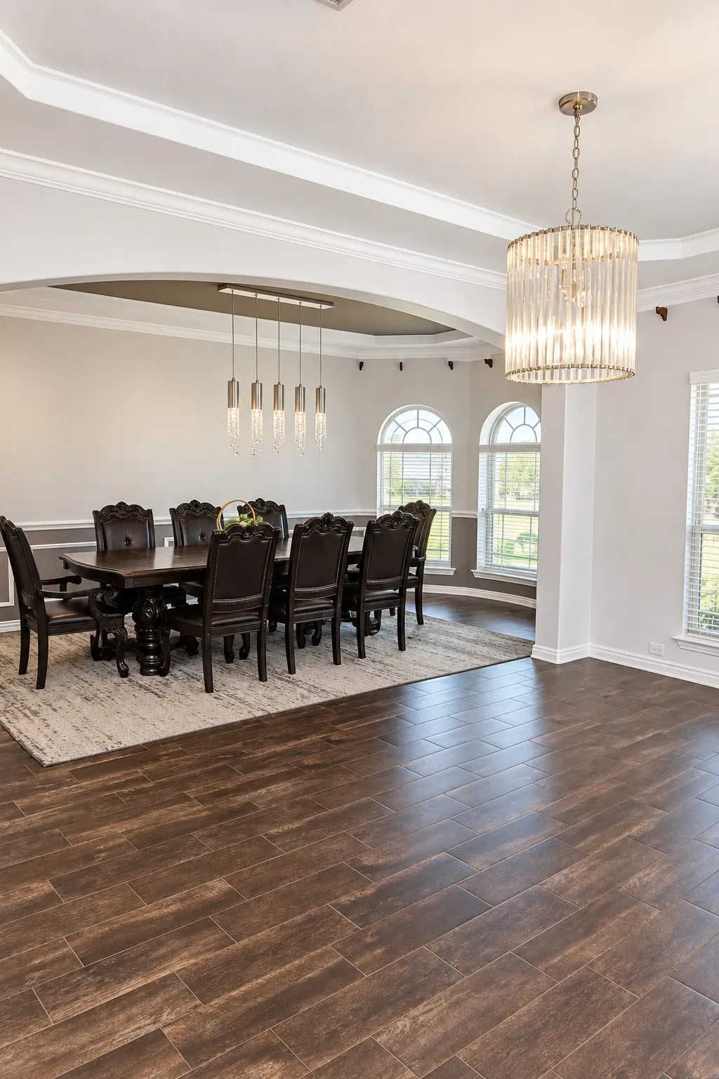 Wood-finish flooring throughout, featuring a drum chandelier, recessed lighting, and arched entryways with detailed trim work