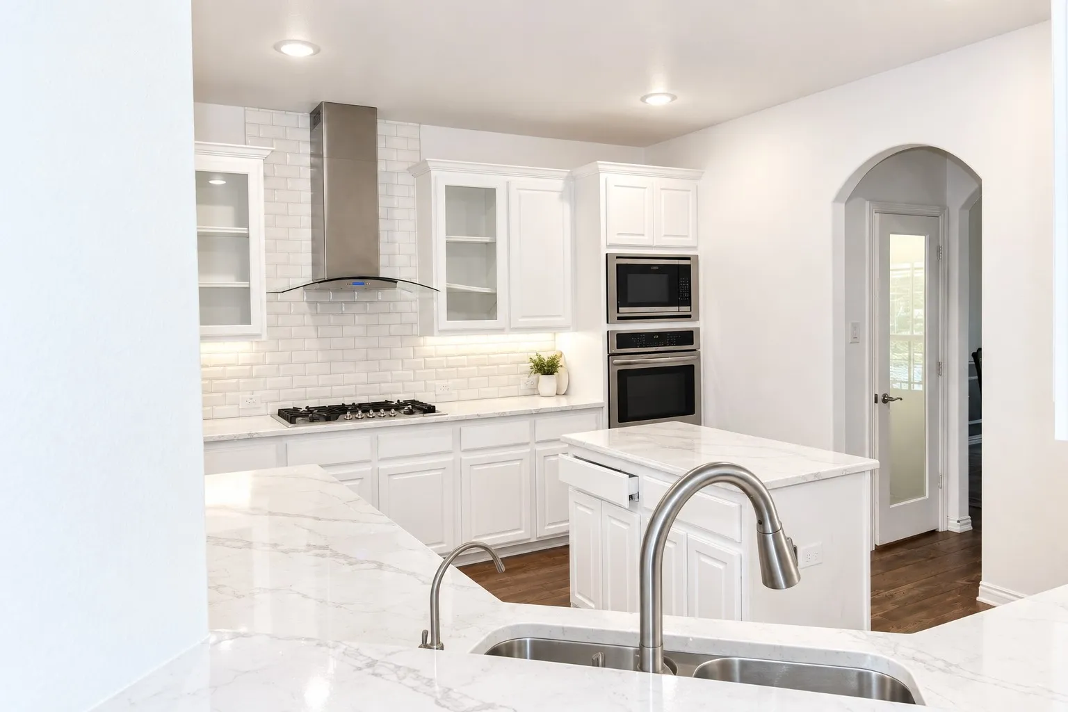 White cabinetry, stainless steel appliances, marble-look countertops, subway tile backsplash, and recessed lighting