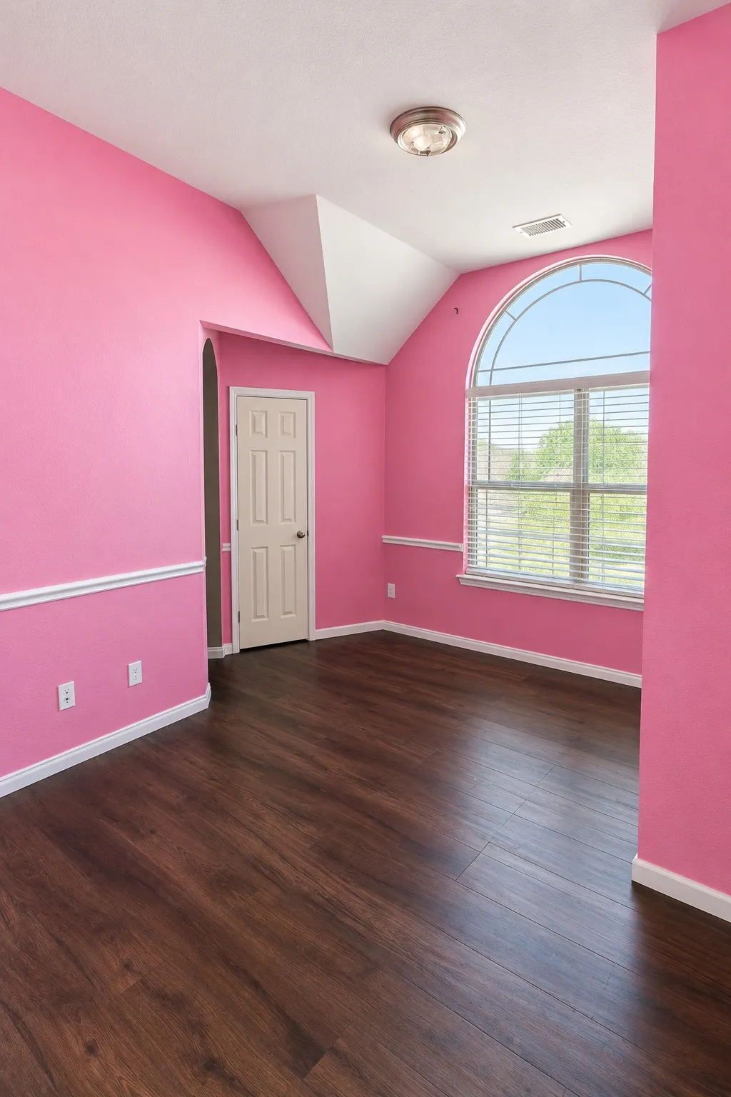 Custom painted room that can be painted white upon closing. Wood-finish flooring, arched window with horizontal blinds, flush mount ceiling light, and crown molding