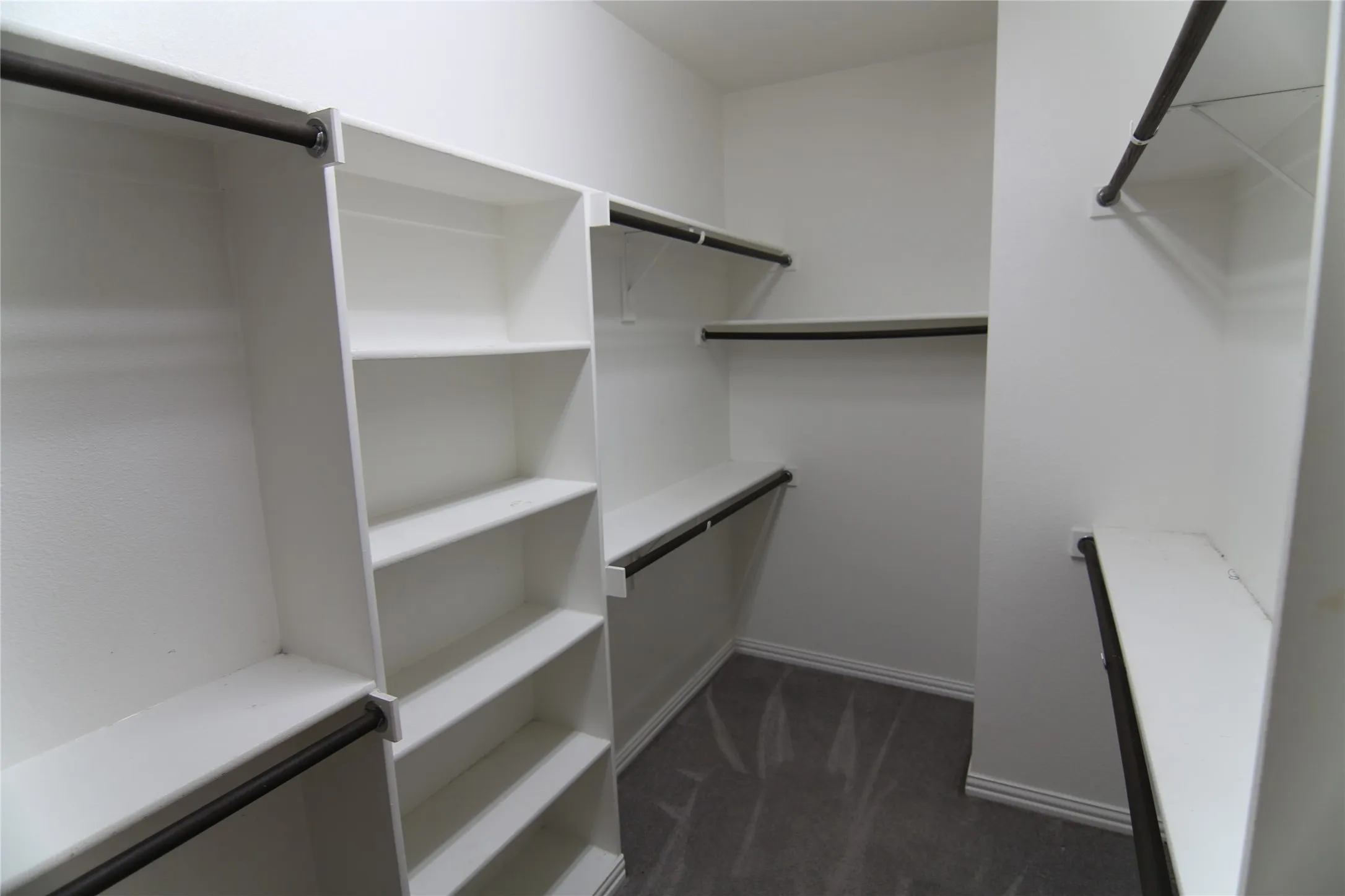 Custom closet system with integrated shelving, multiple hanging rods, and grey carpeting
