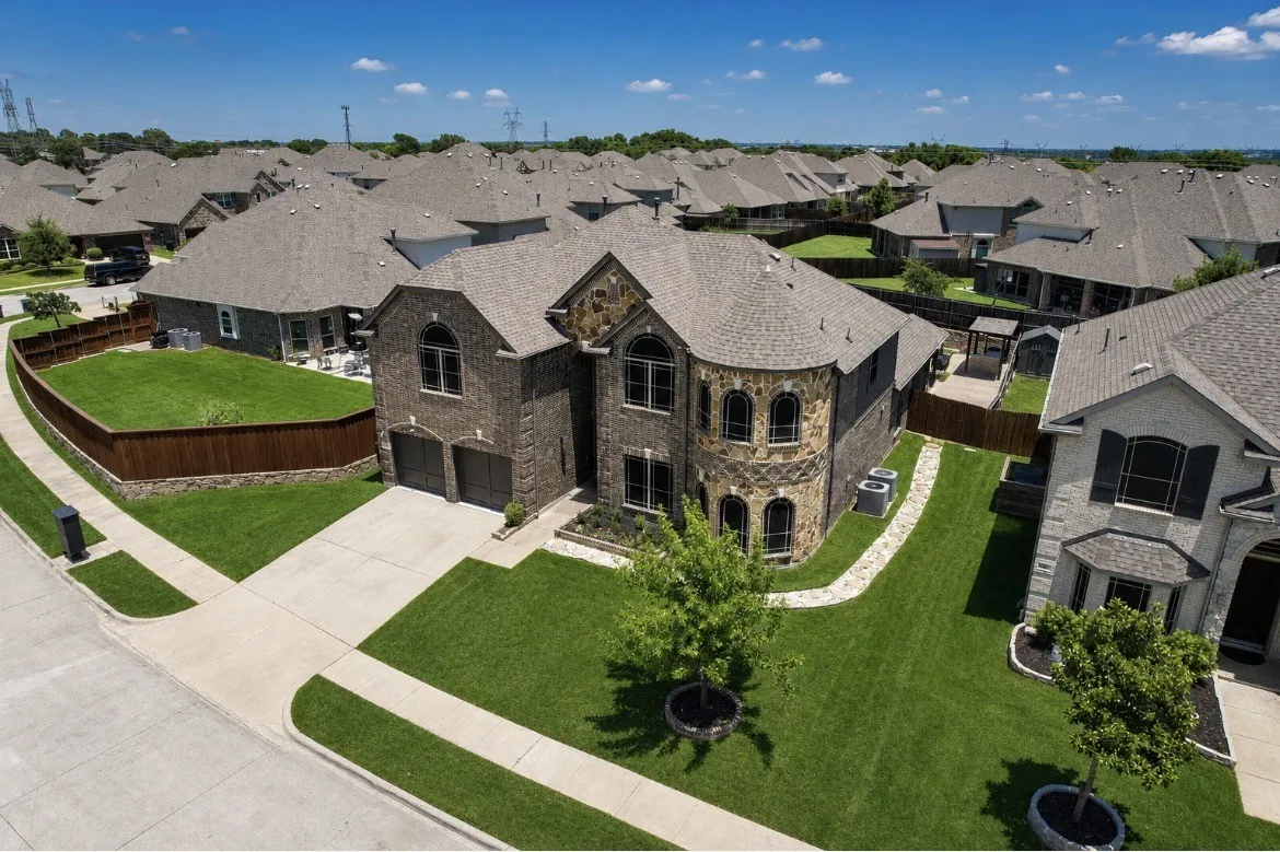 Brick and stone-clad residence featuring an arched entry, a two-car garage, and a concrete driveway