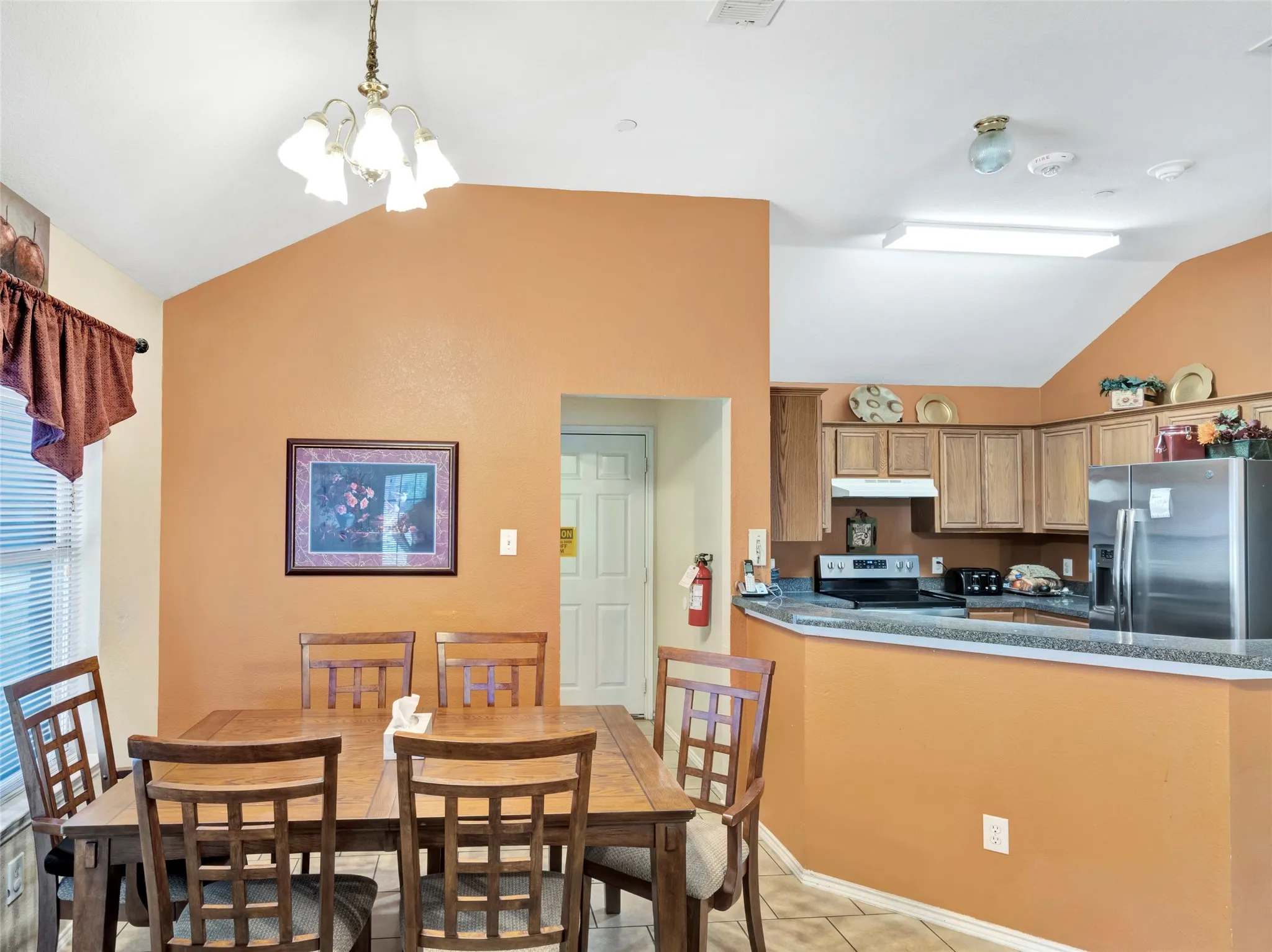 Kitchen featuring wood-finish cabinetry, stainless steel appliances, and a breakfast bar with a stone-finish countertop