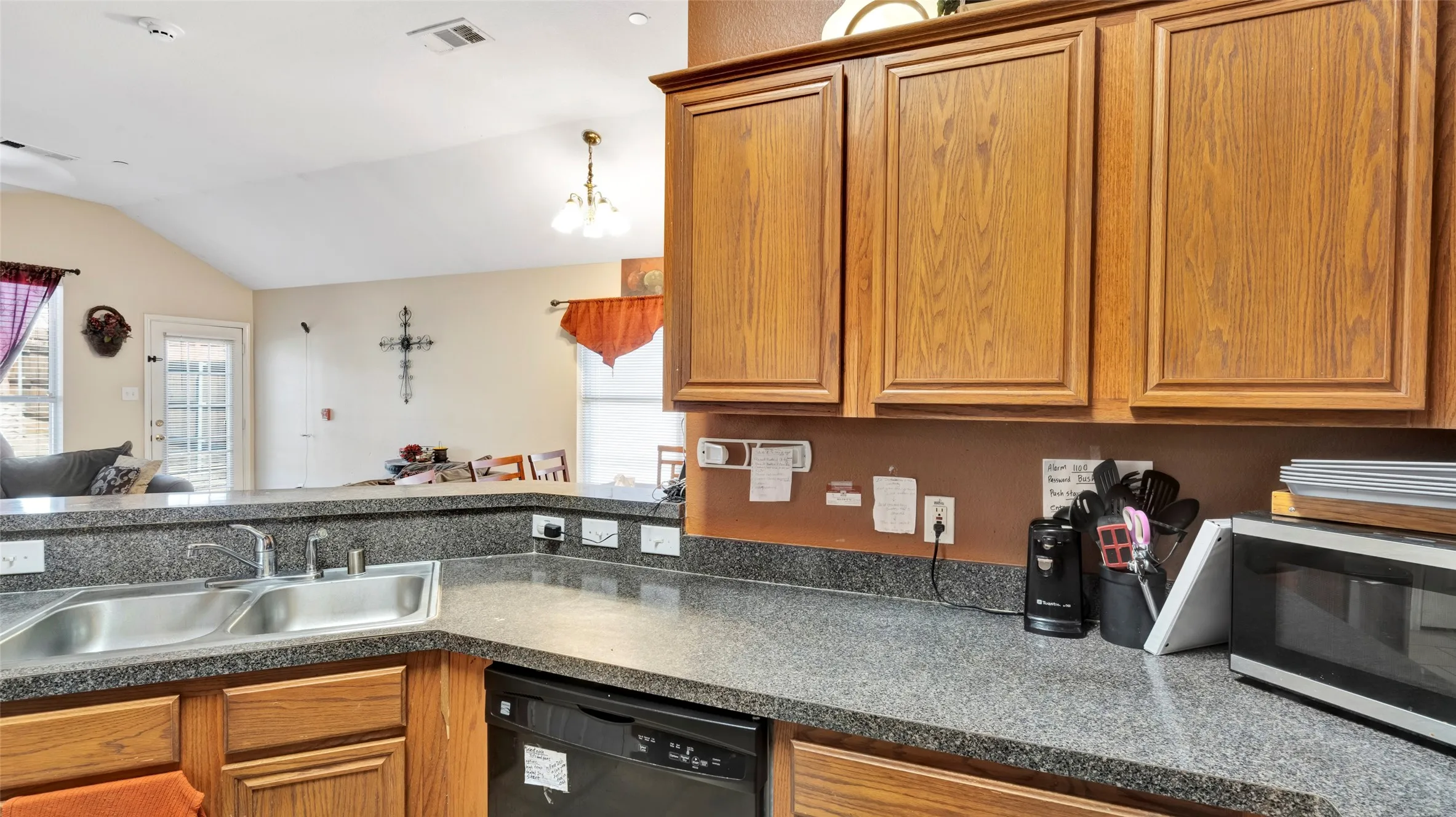 Kitchen featuring wood cabinetry, a double basin stainless steel sink, and speckled countertops