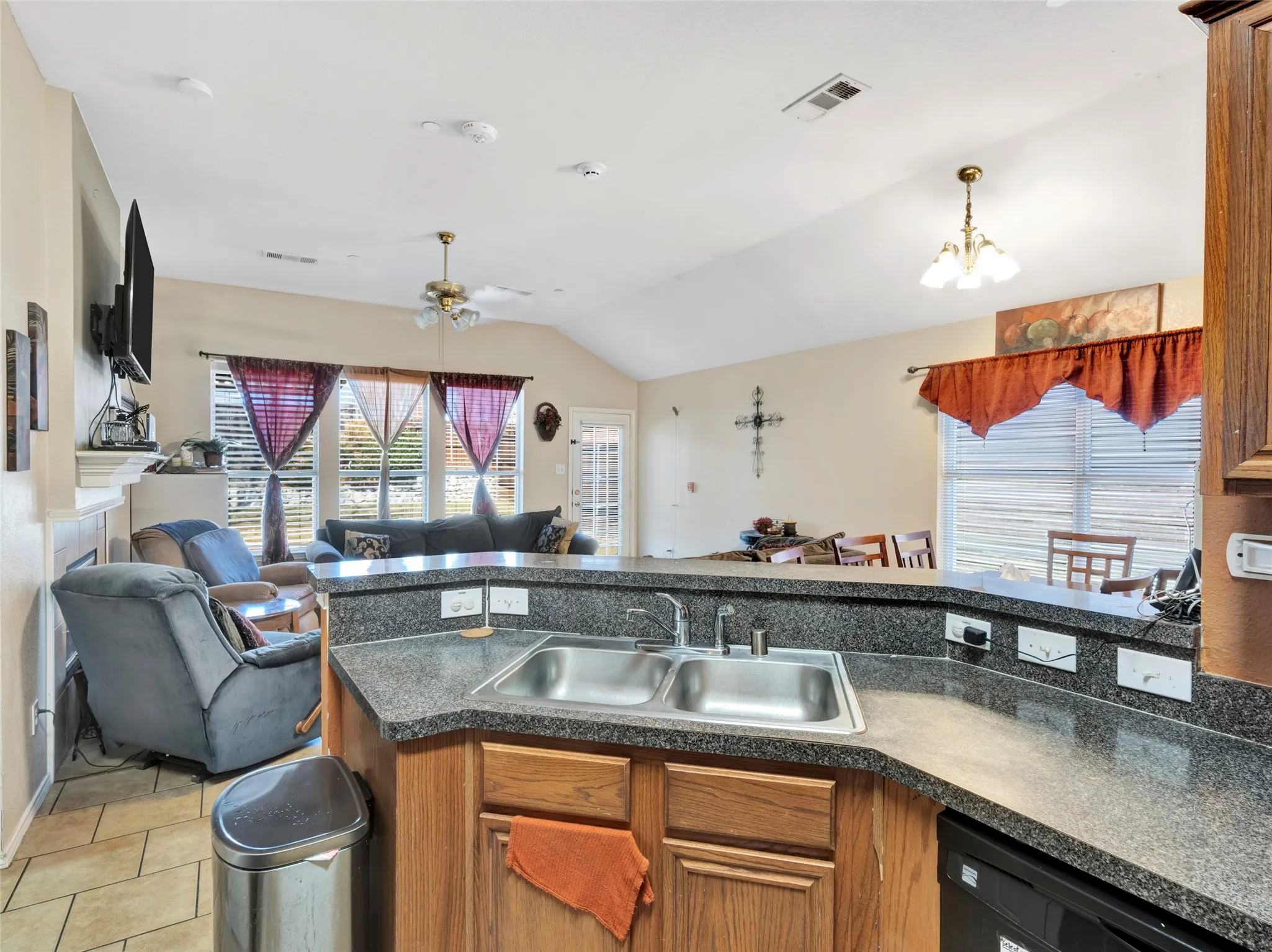 Kitchen with wood-finish cabinetry, a double basin stainless steel sink, and speckled countertop