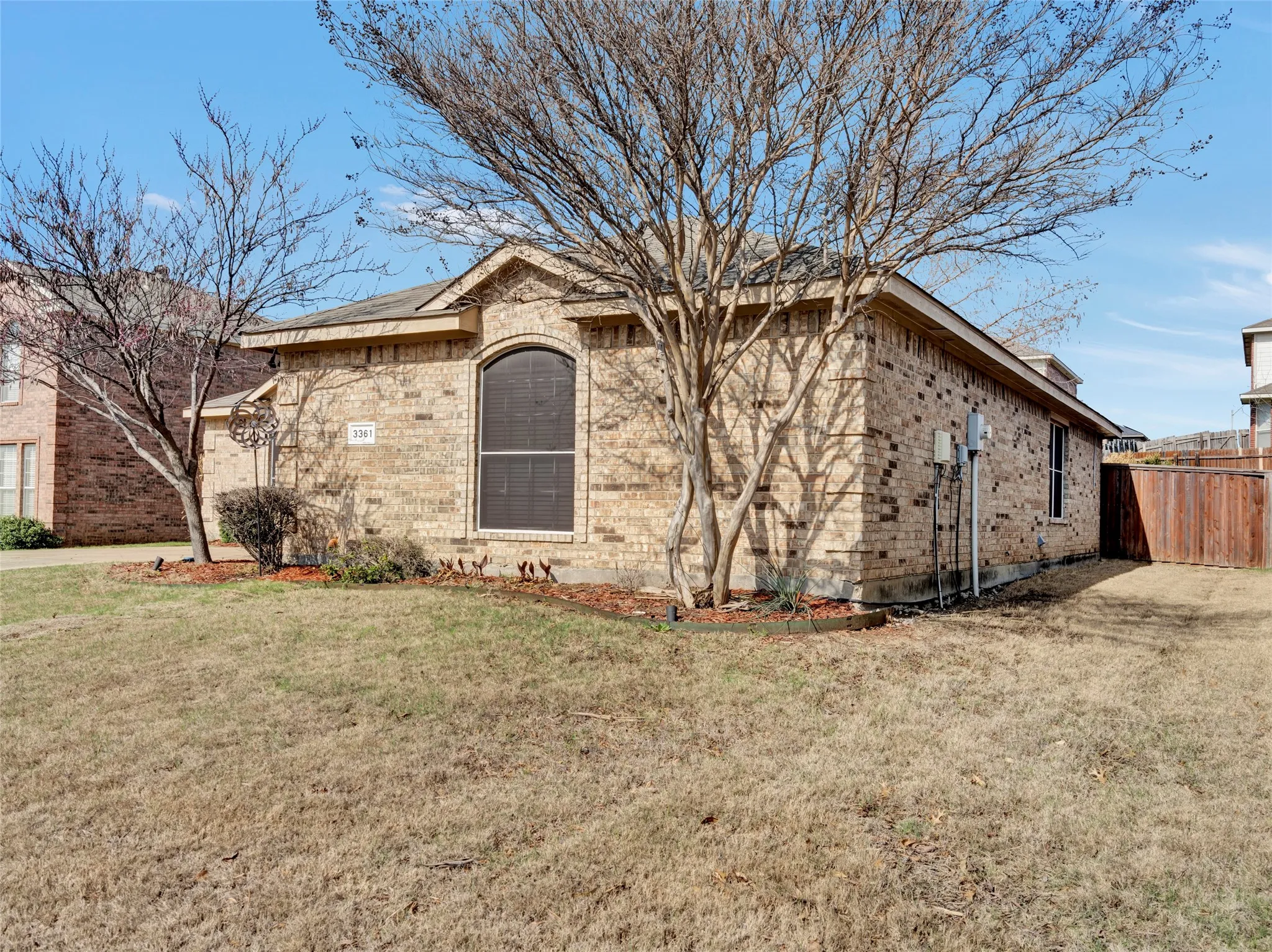 Brick exterior with an arched window and a privacy fence