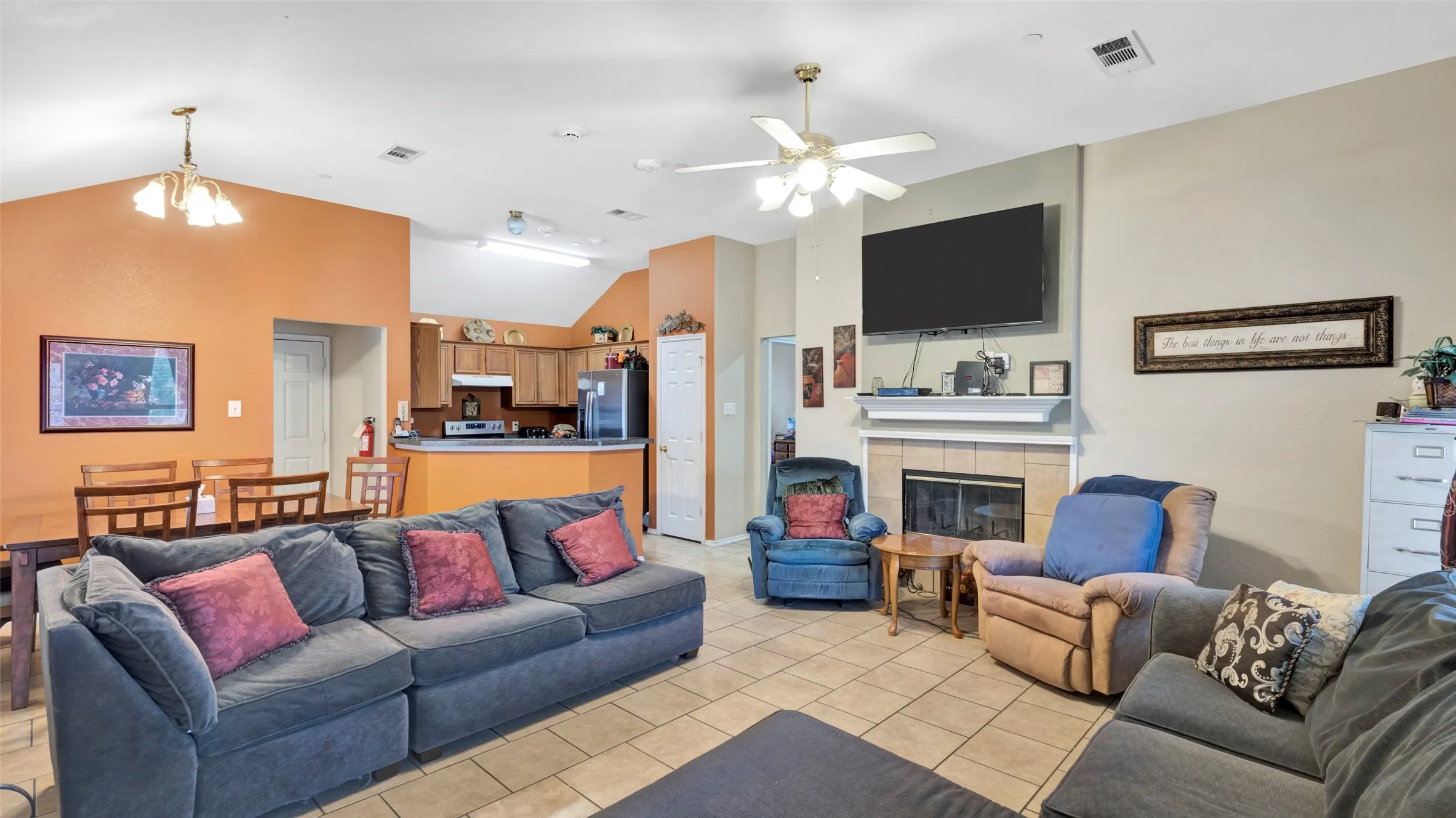 Open concept living area featuring vaulted ceilings, tile flooring, and a fireplace with a mantel