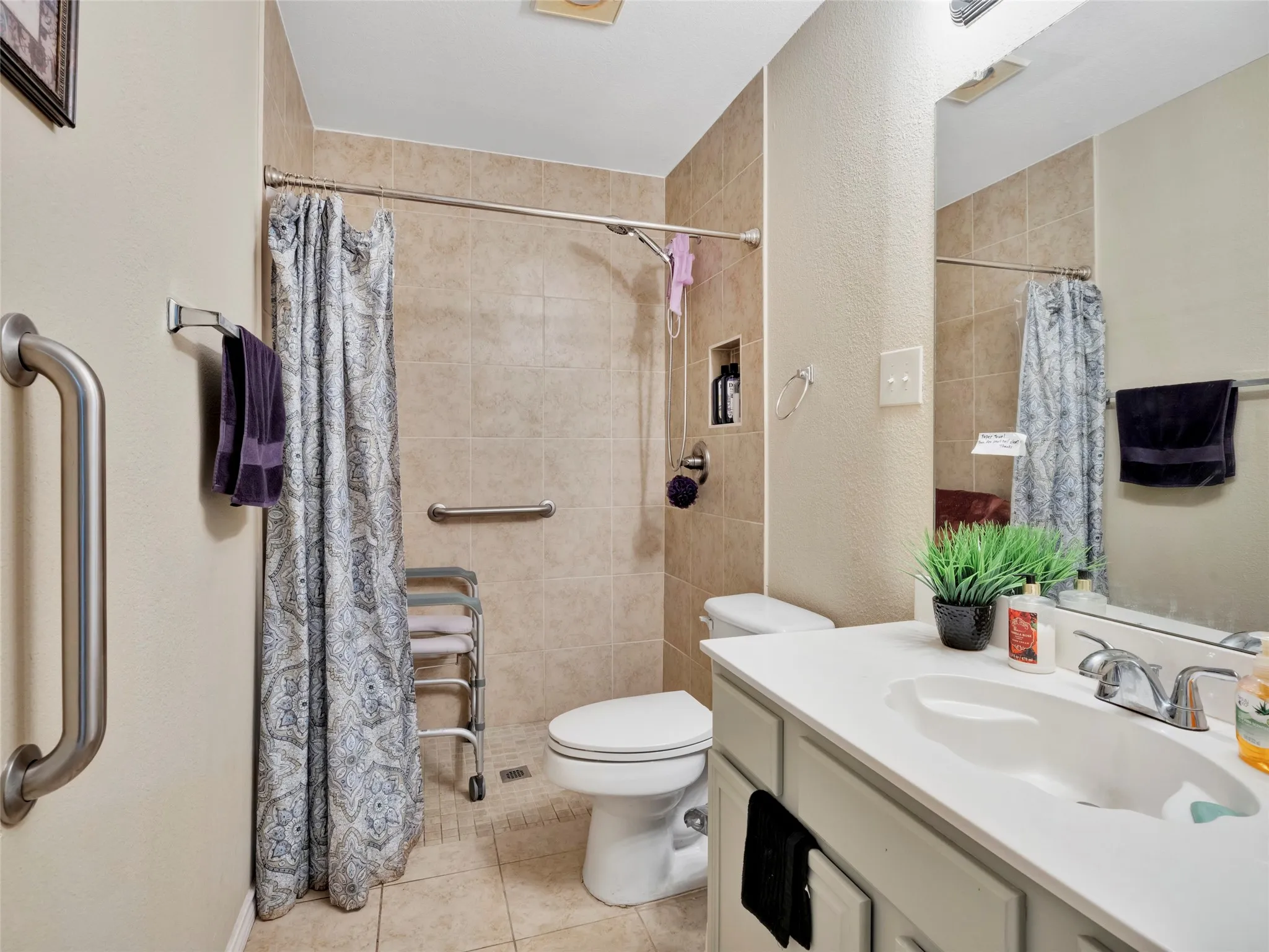 Tile flooring and shower surround, vanity with integrated sink, and an embedded shower niche