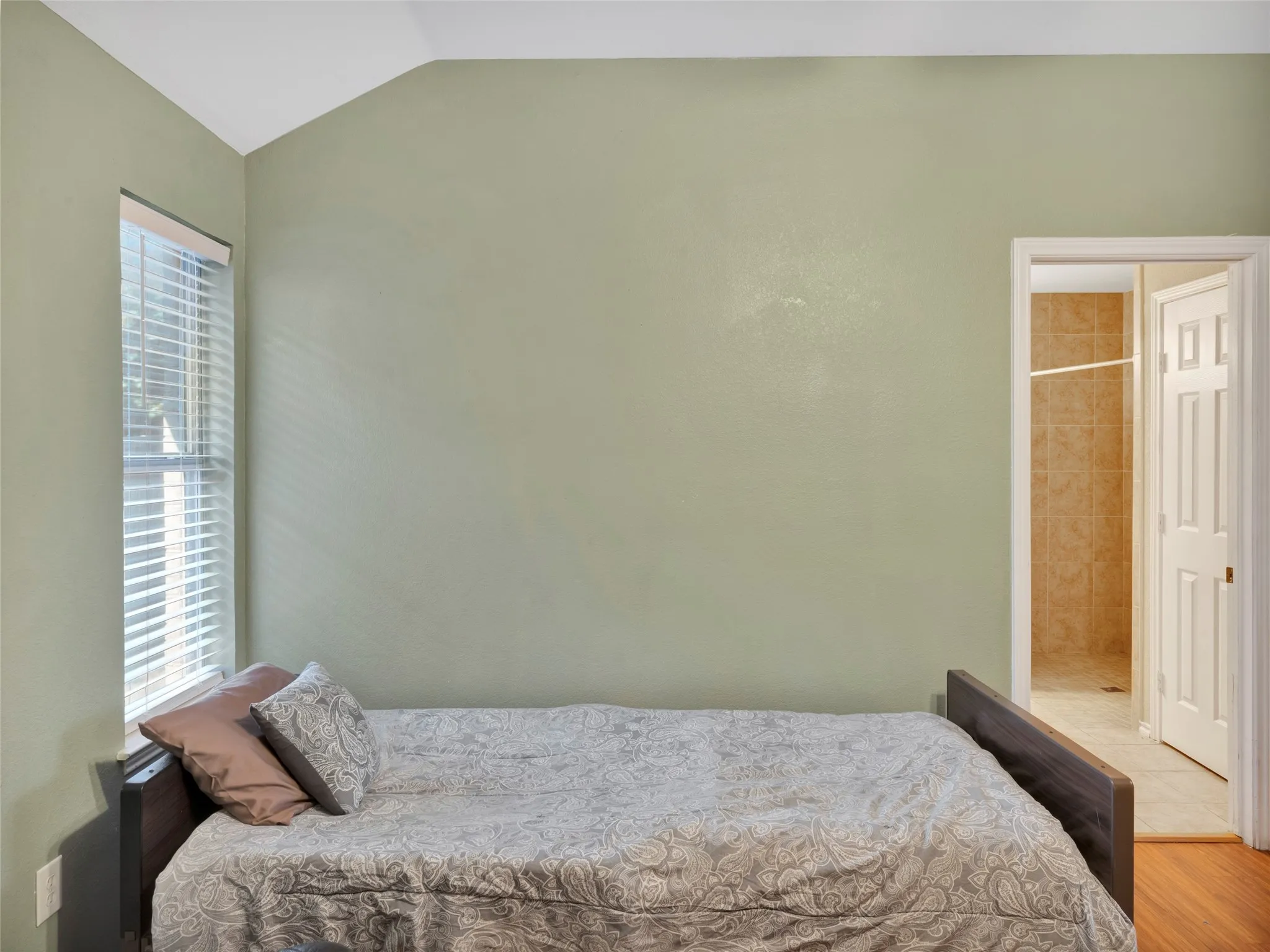 Vaulted ceiling accentuates the room, complemented by a window with blinds providing natural light