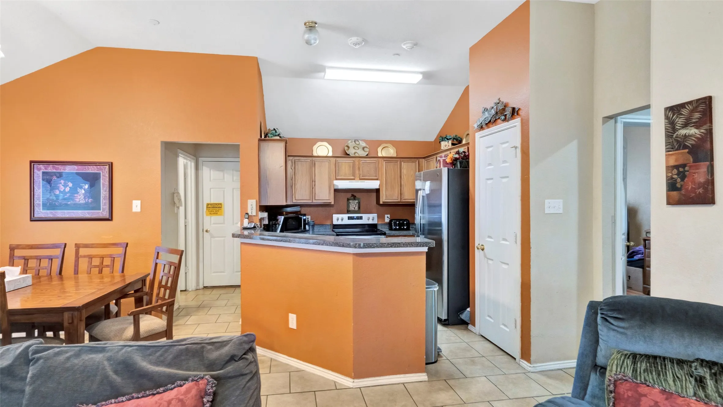 Vaulted ceiling, kitchen with wood-finish cabinetry, built-in appliances, and a breakfast bar