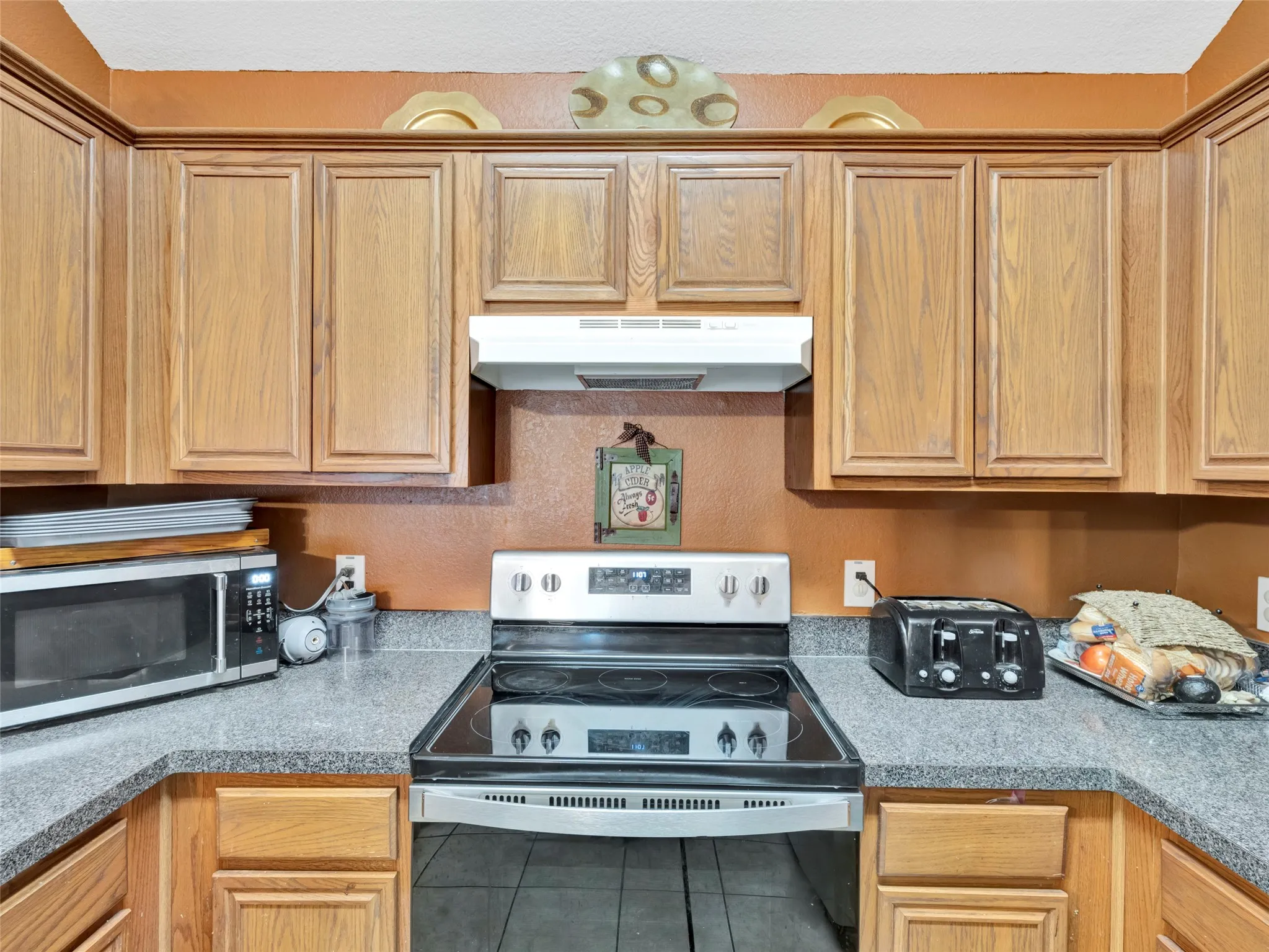 U-shaped counter featuring wood-finish cabinetry, a built-in range, and a range hood