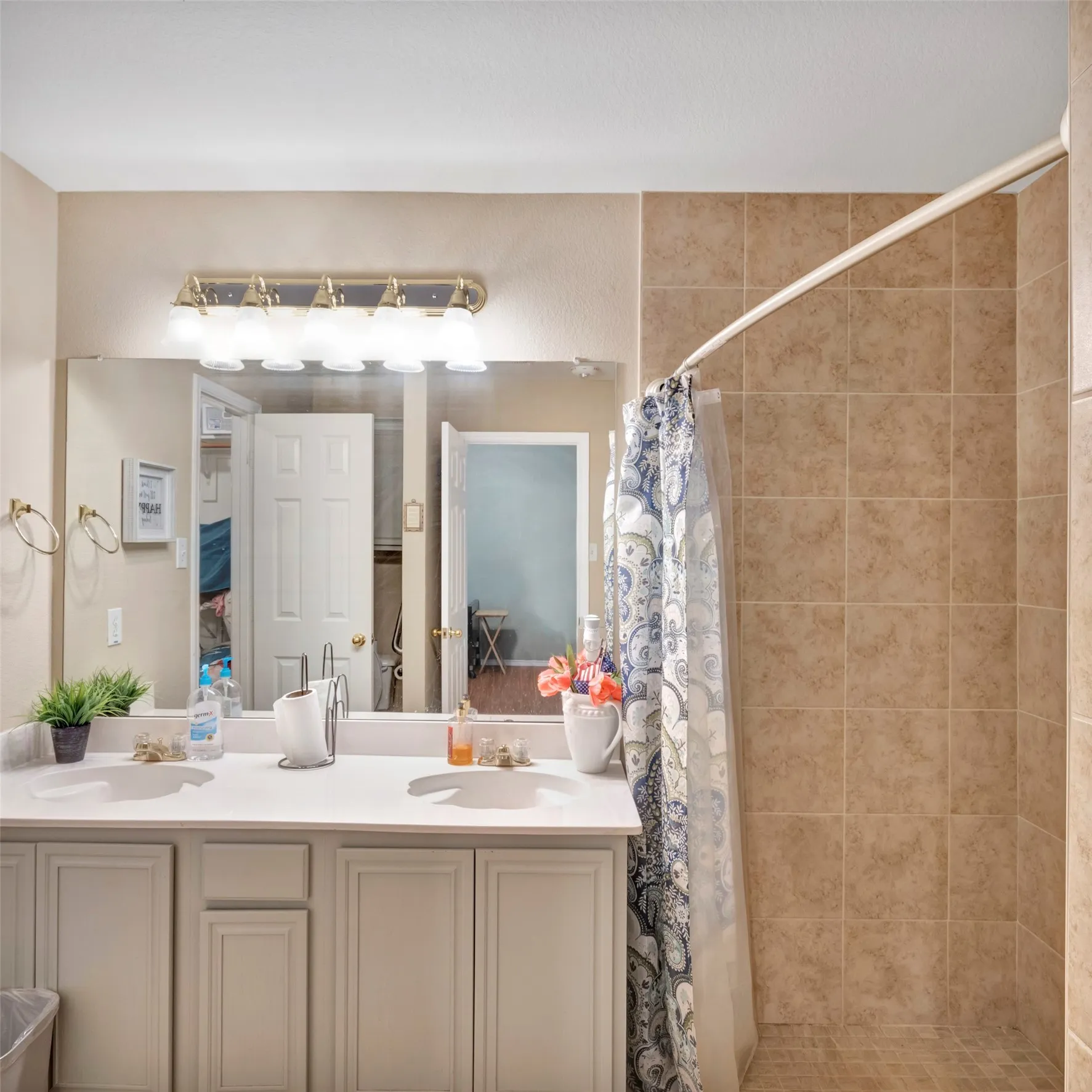 Dual vanity with integrated sinks, light-toned cabinetry, and a full-width mirror