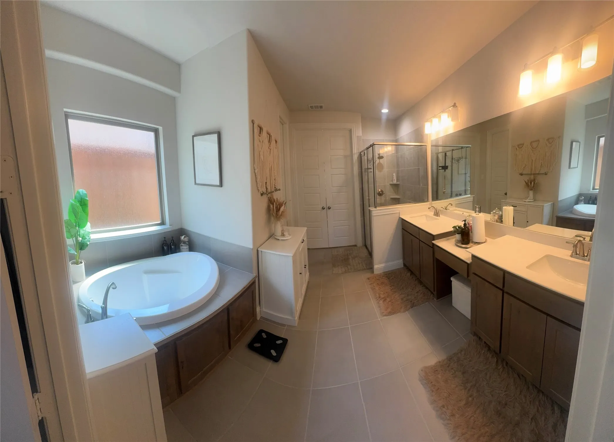Bathroom featuring a built-in oval soaking tub, a dual vanity with undermount sinks, and a glass-enclosed shower with tile surround