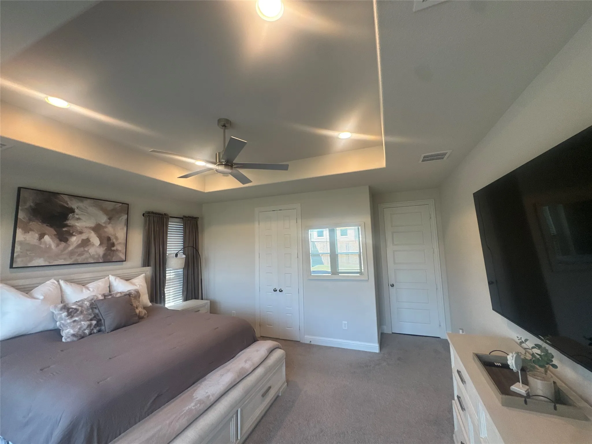 Recessed lighting illuminates a tray ceiling with a contemporary ceiling fan