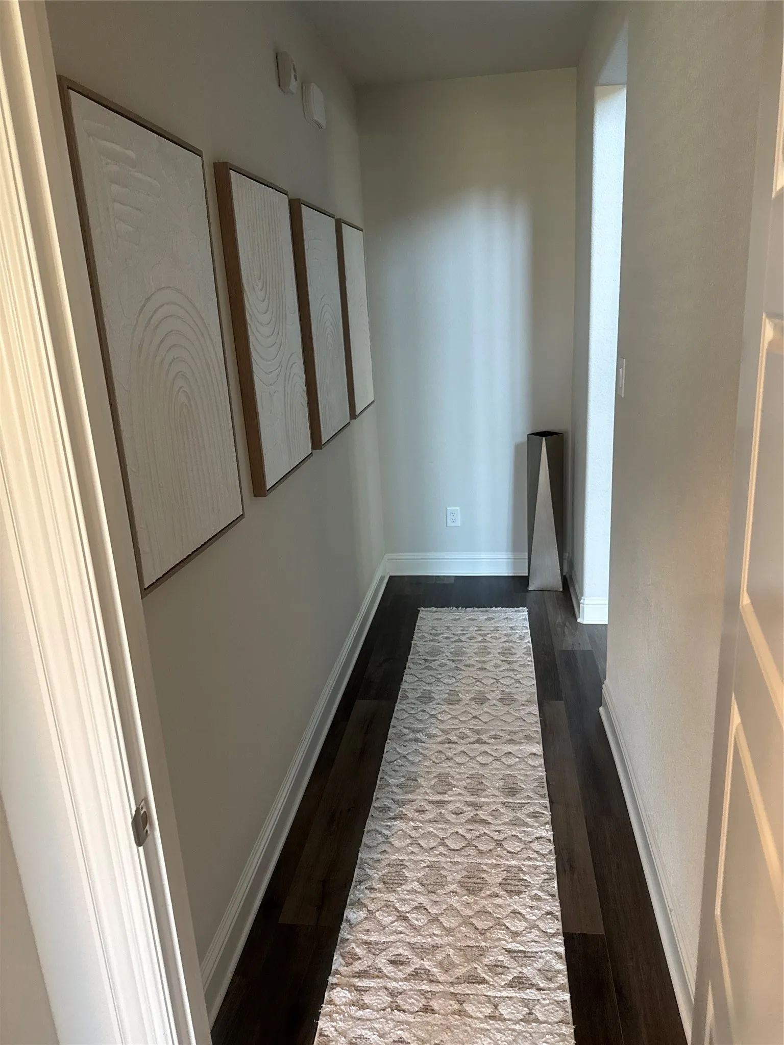 Hallway featuring dark wood-finish flooring and light-toned walls