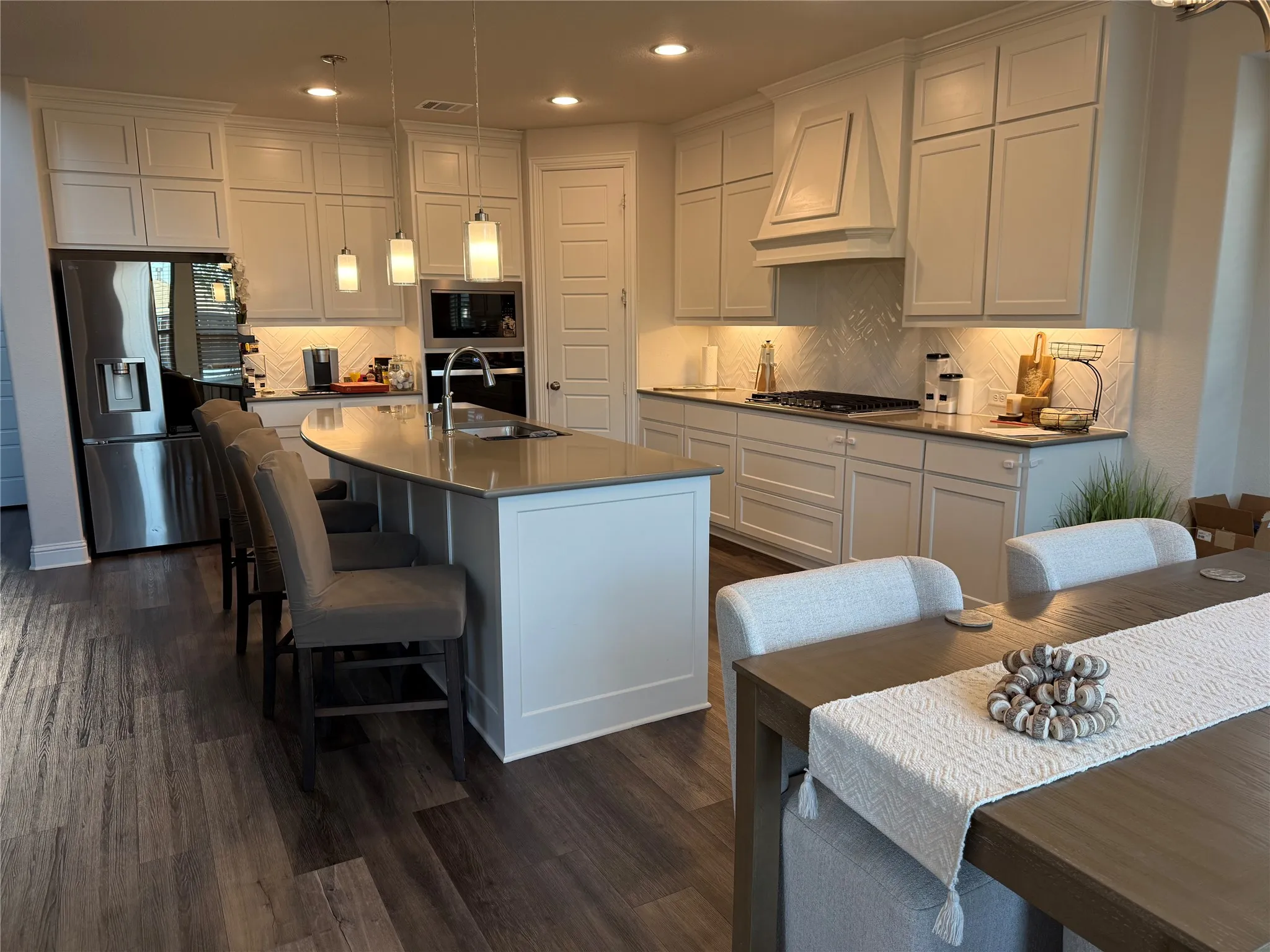 Contemporary kitchen featuring an oversized island with a built-in sink and pendant lighting