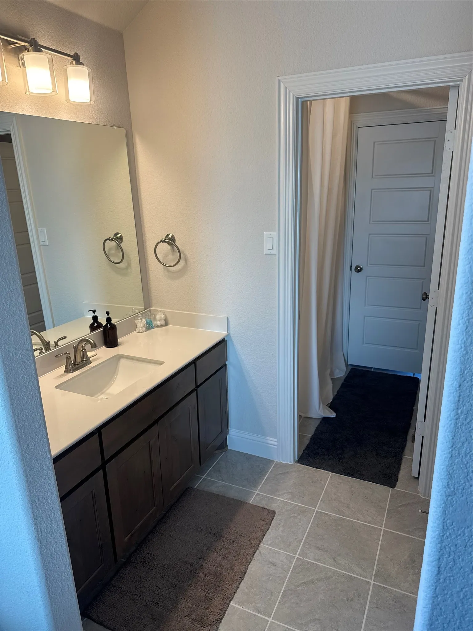 Bathroom featuring a single vanity with dark wood-finish cabinetry, a white countertop, and an undermount sink