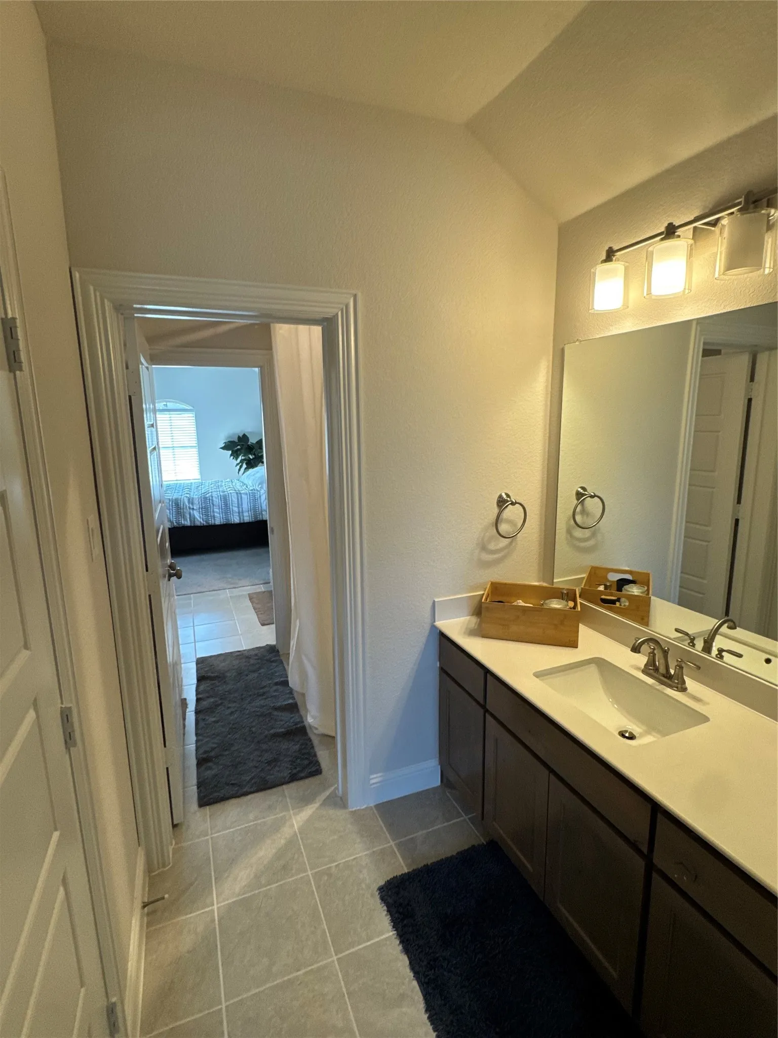Bathroom vanity with an integrated sink, broad mirror, and modern light fixture