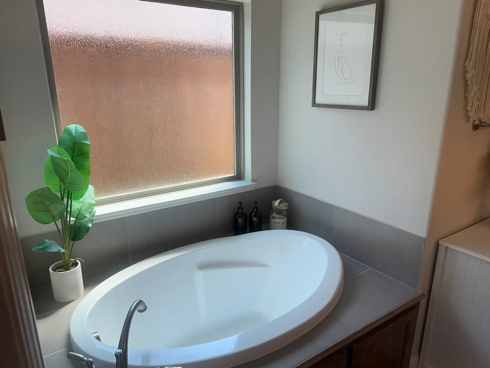 Oval soaking tub with deck-mounted chrome faucet, set against a tiled surround