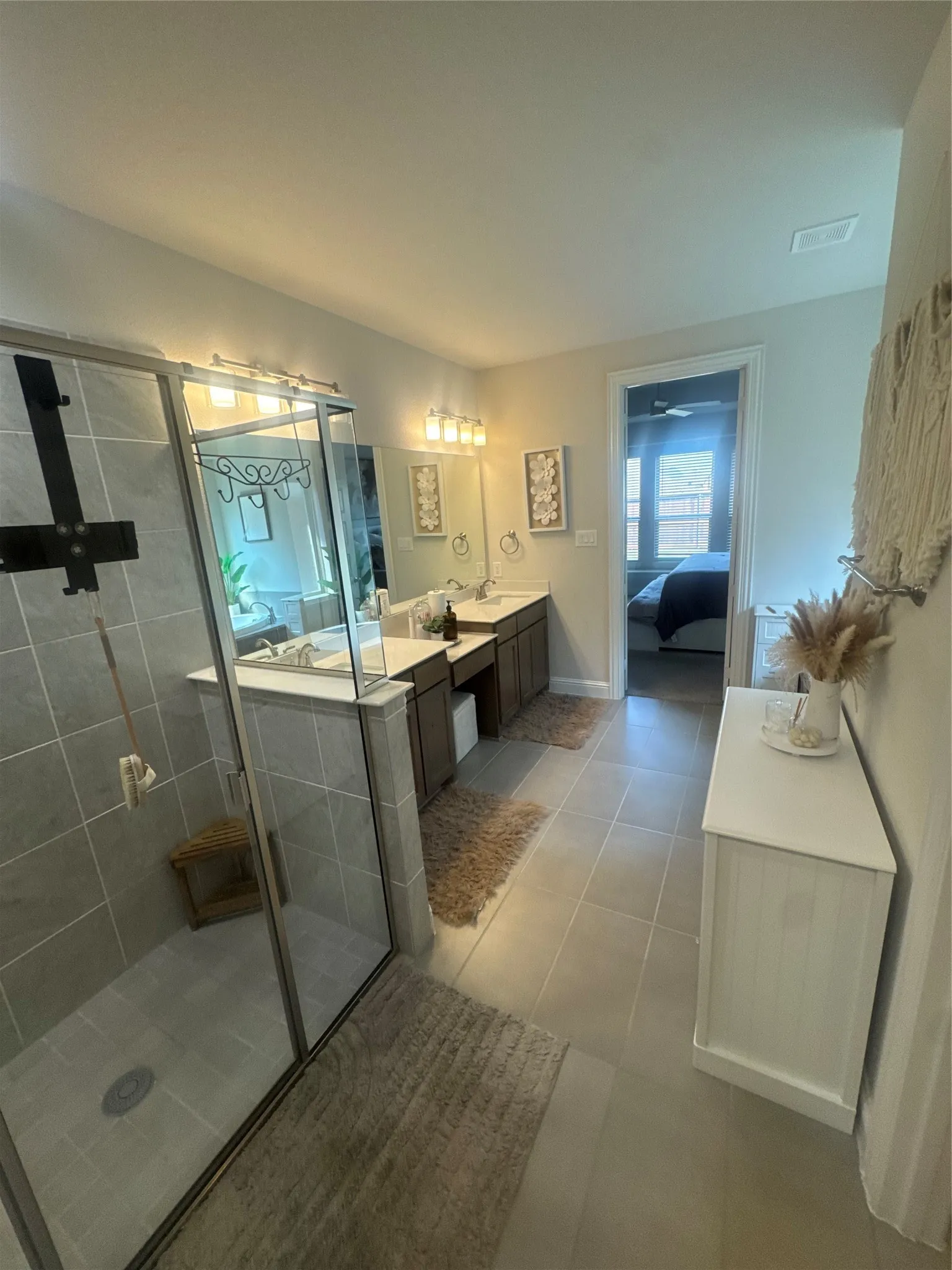 Bathroom featuring a spacious glass-enclosed shower with tile surround, dual vanity with undermount sinks, and tile flooring