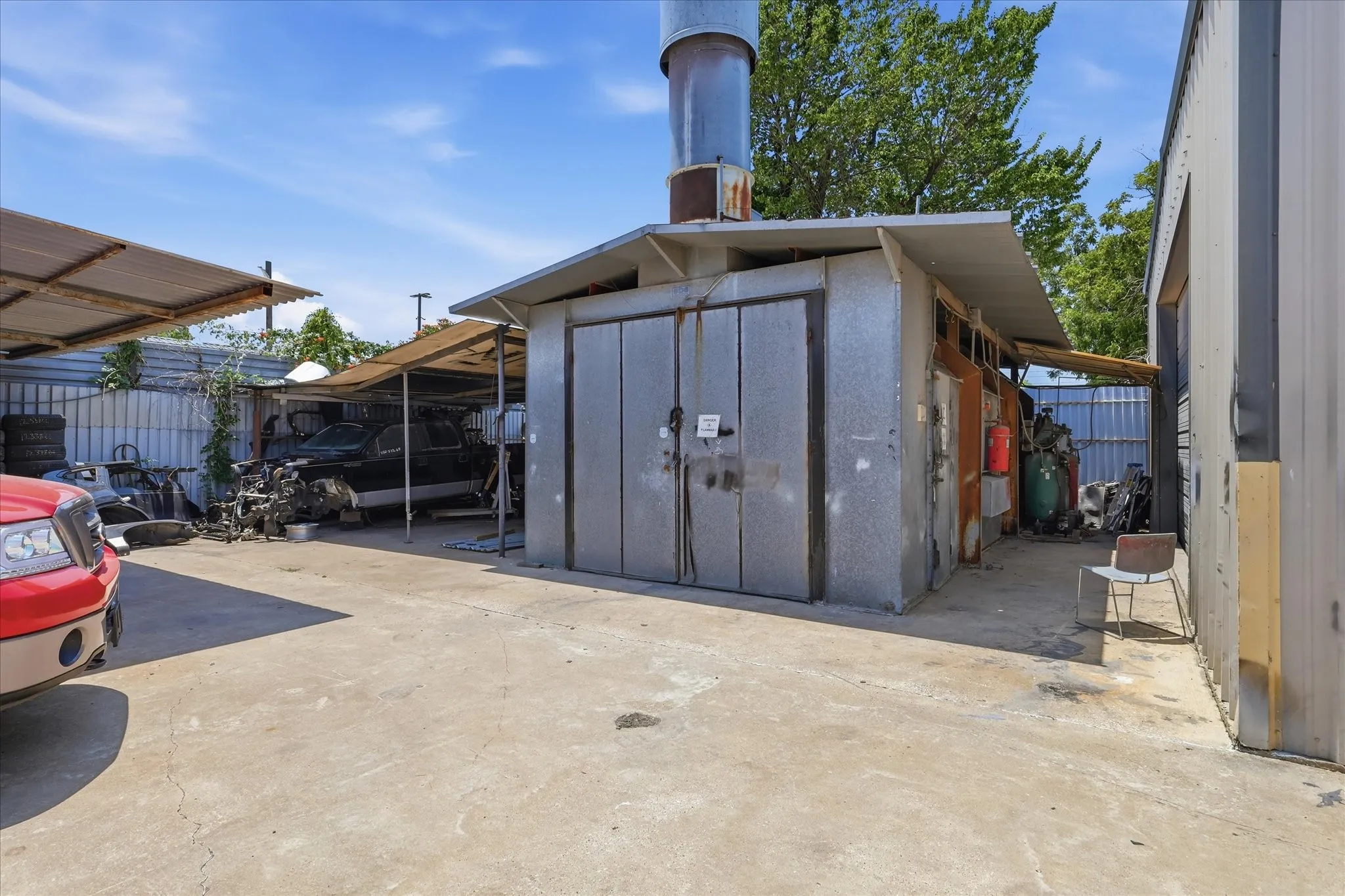 Industrial building featuring a tall exhaust stack, corrugated metal siding, and a concrete slab foundation