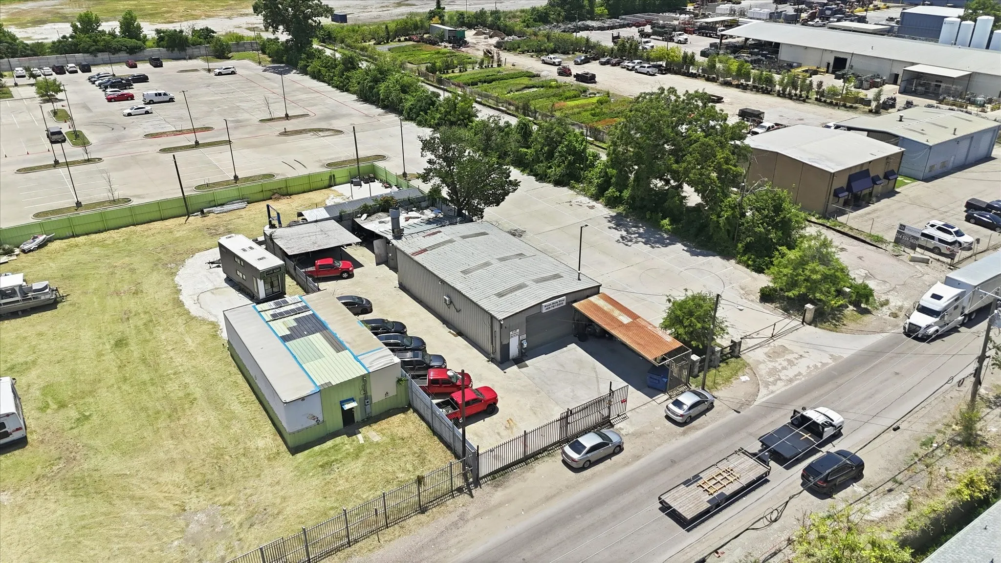 Expansive commercial property featuring multiple buildings, paved parking areas, and convenient road frontage