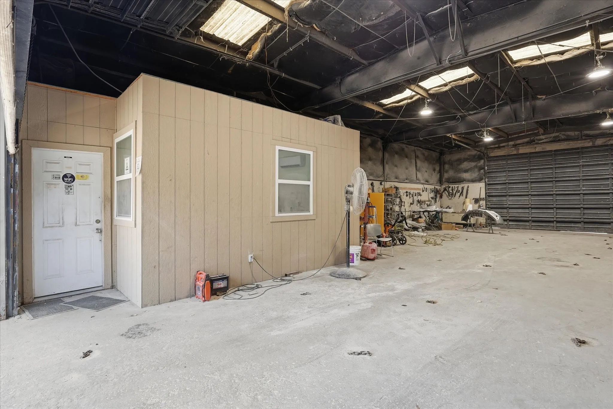 Spacious commercial interior featuring a built-in office structure with two windows and a white entry door