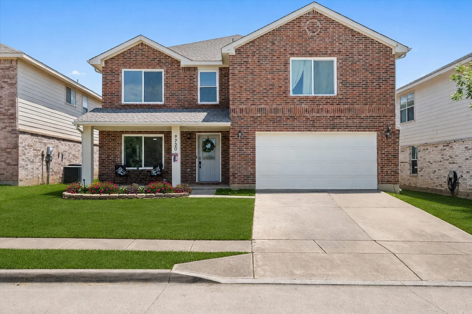 Beautiful front exterior featuring a welcoming front porch. Grass and flower beds have been virtually enhanced.