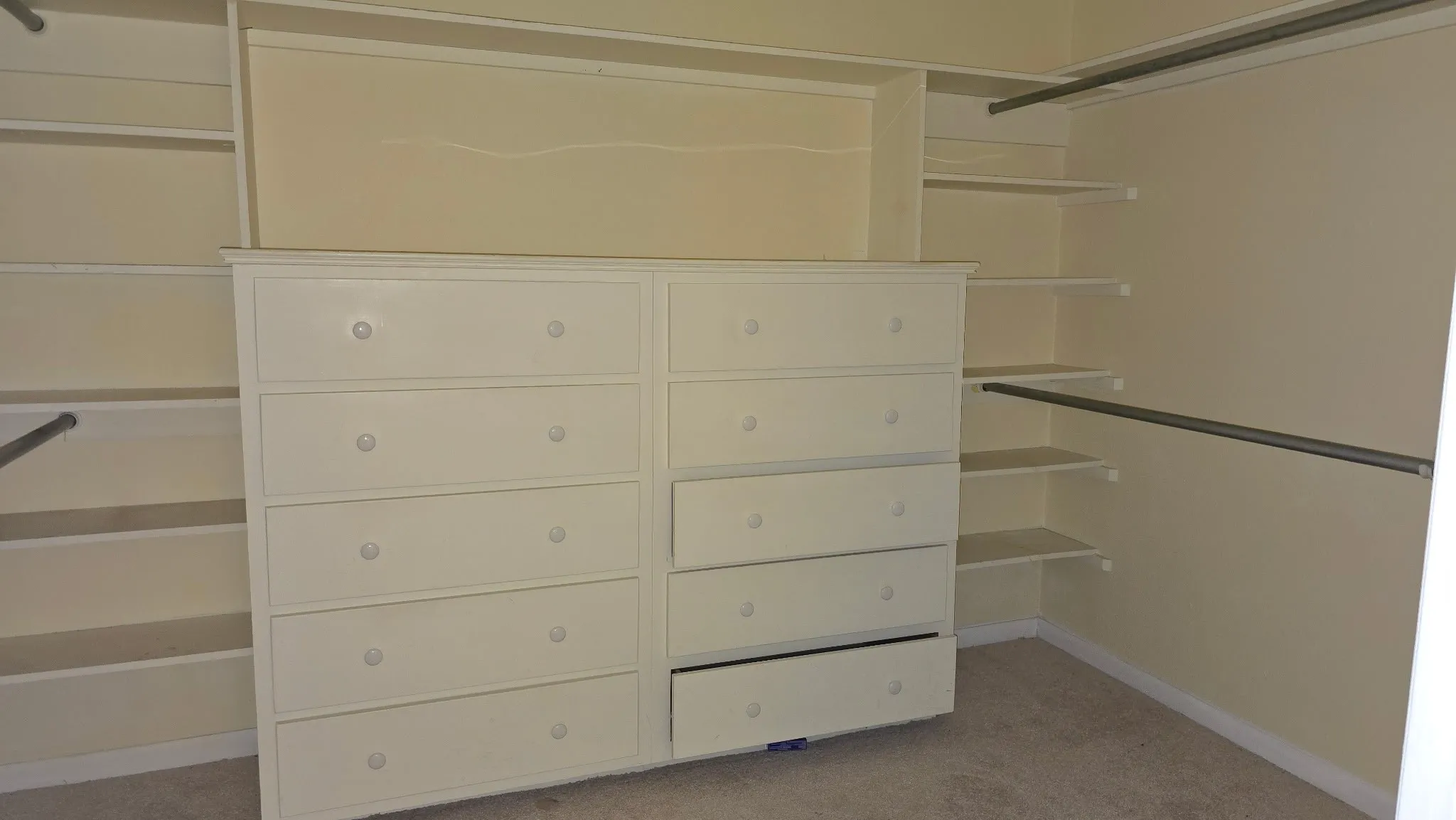 Custom closet organization system featuring built-in shelving, hanging rods, and a large central dresser with multiple drawers