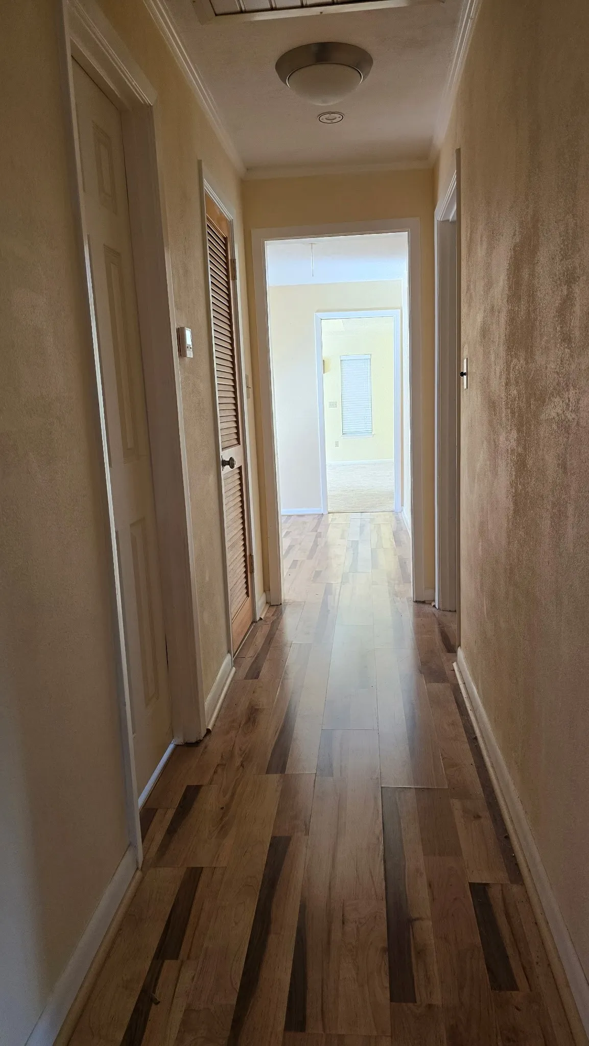 Hallway featuring wood-finish flooring, white baseboards, and a flush-mount ceiling light fixture