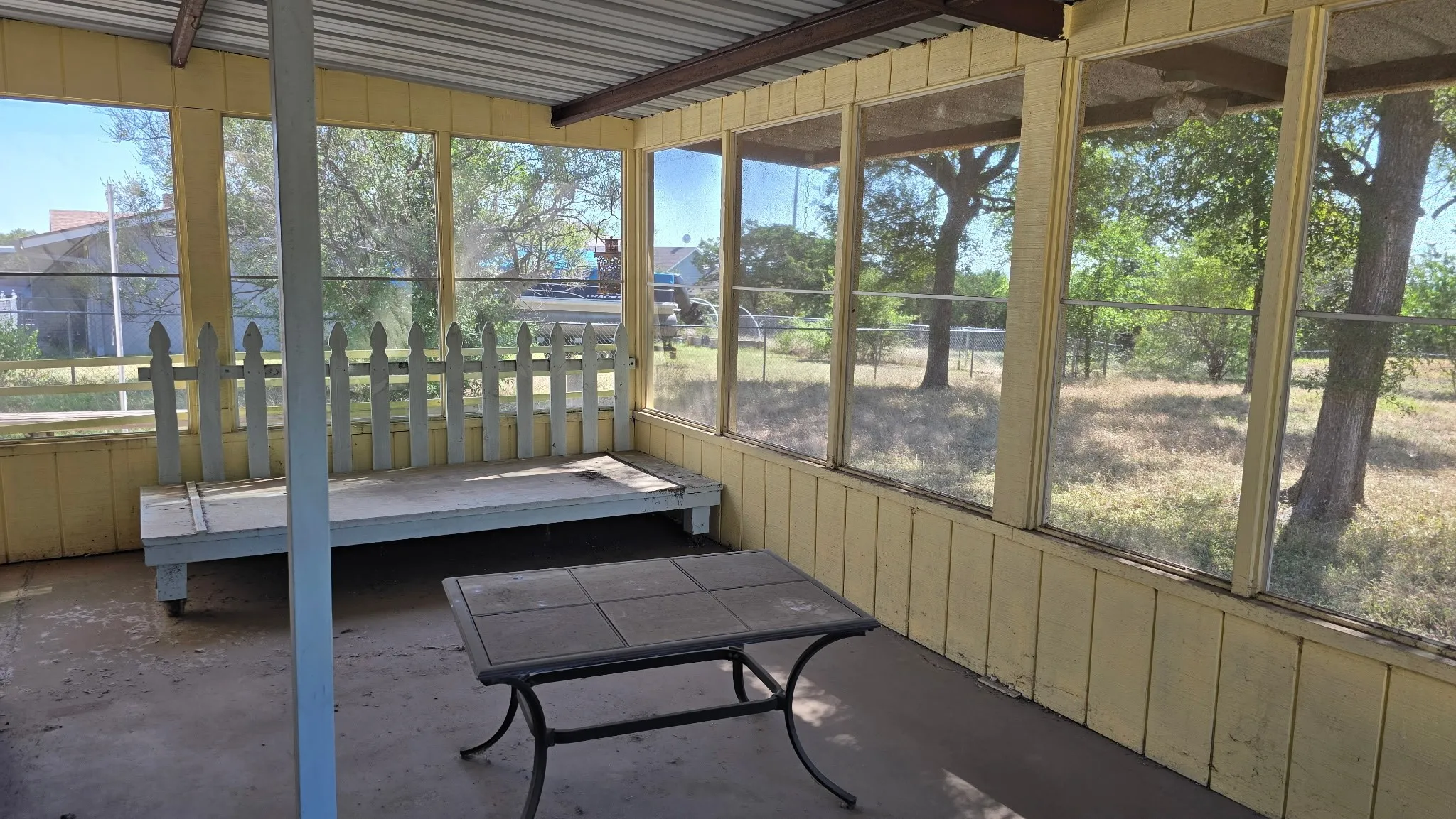 Screened patio featuring a concrete floor, yellow wood paneling, and a metal roof